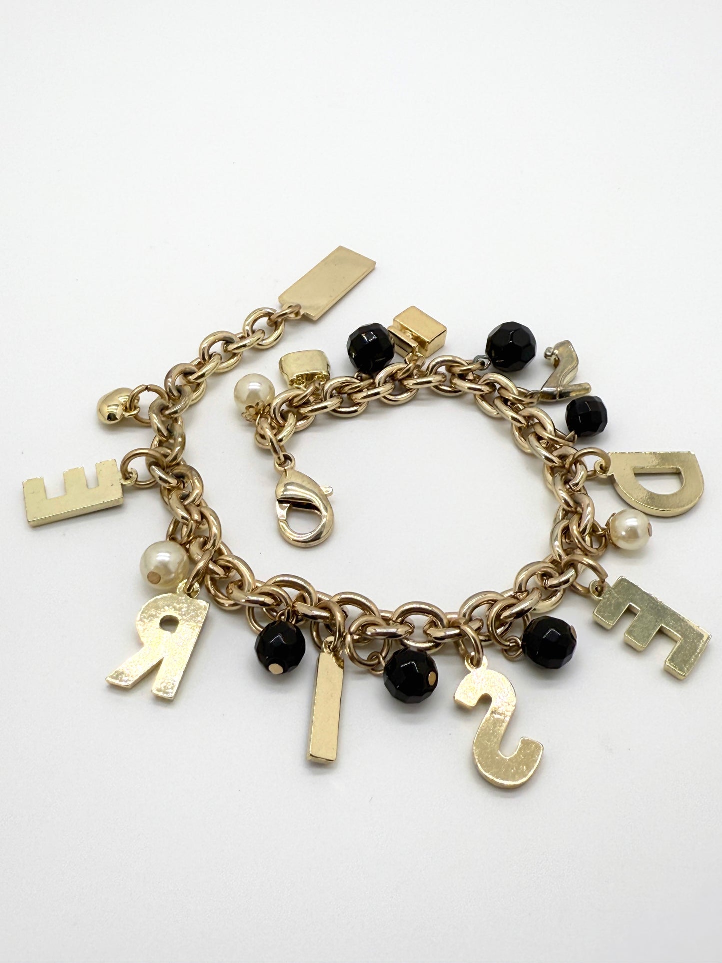 Gold charm bracelet with letters on a white background