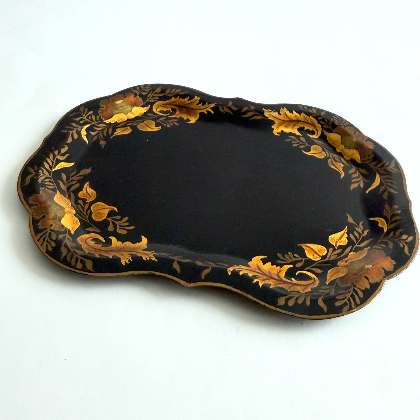 Decorative black tray with gold leaf patterns on a white background