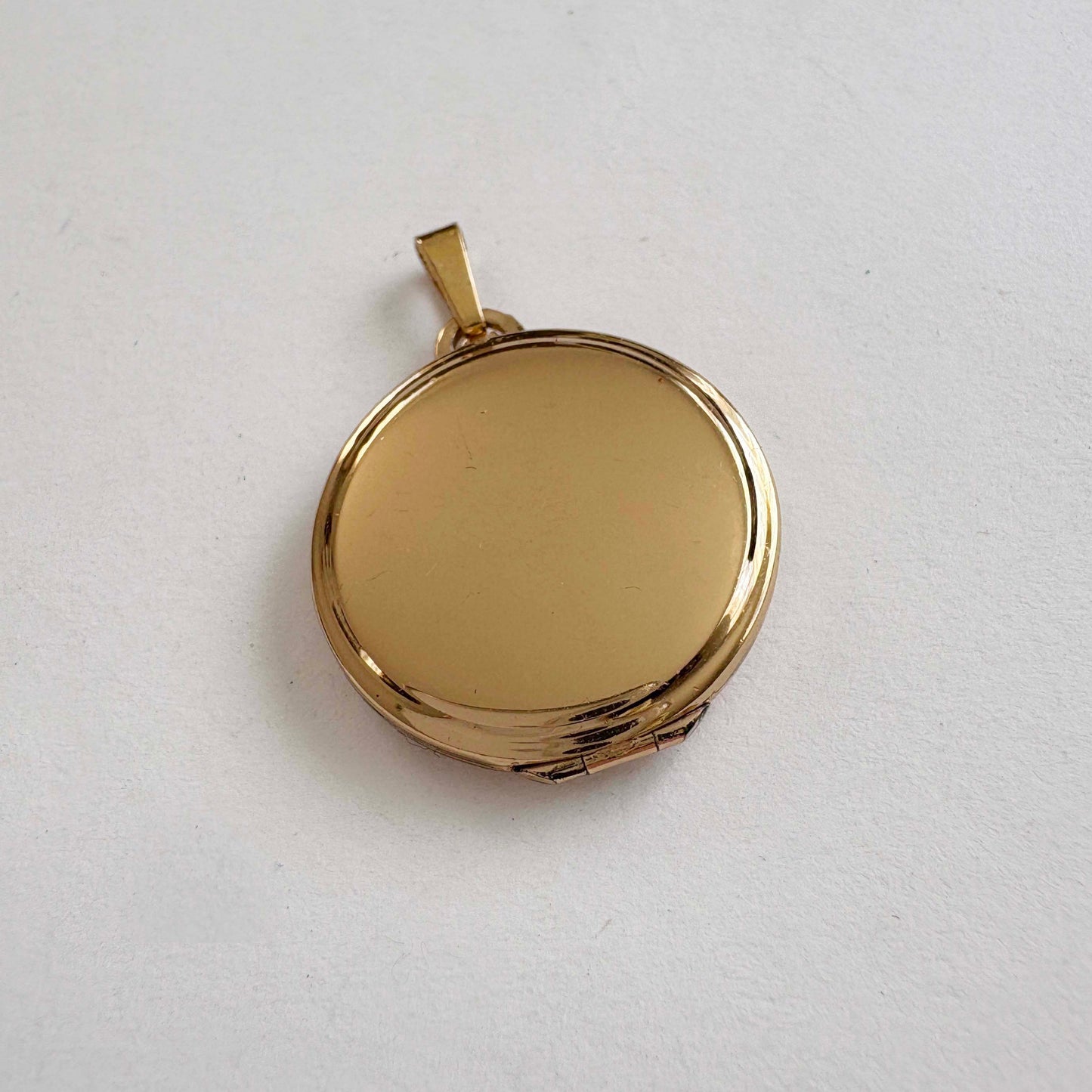 Vintage Monet gold-tone round locket pendant, smooth polished finish, 1980s costume jewelry on white background