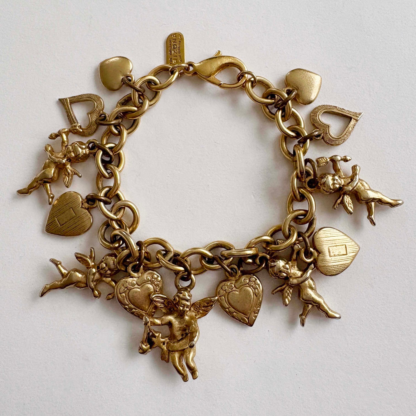 Gold charm bracelet with various charms on a light gray background