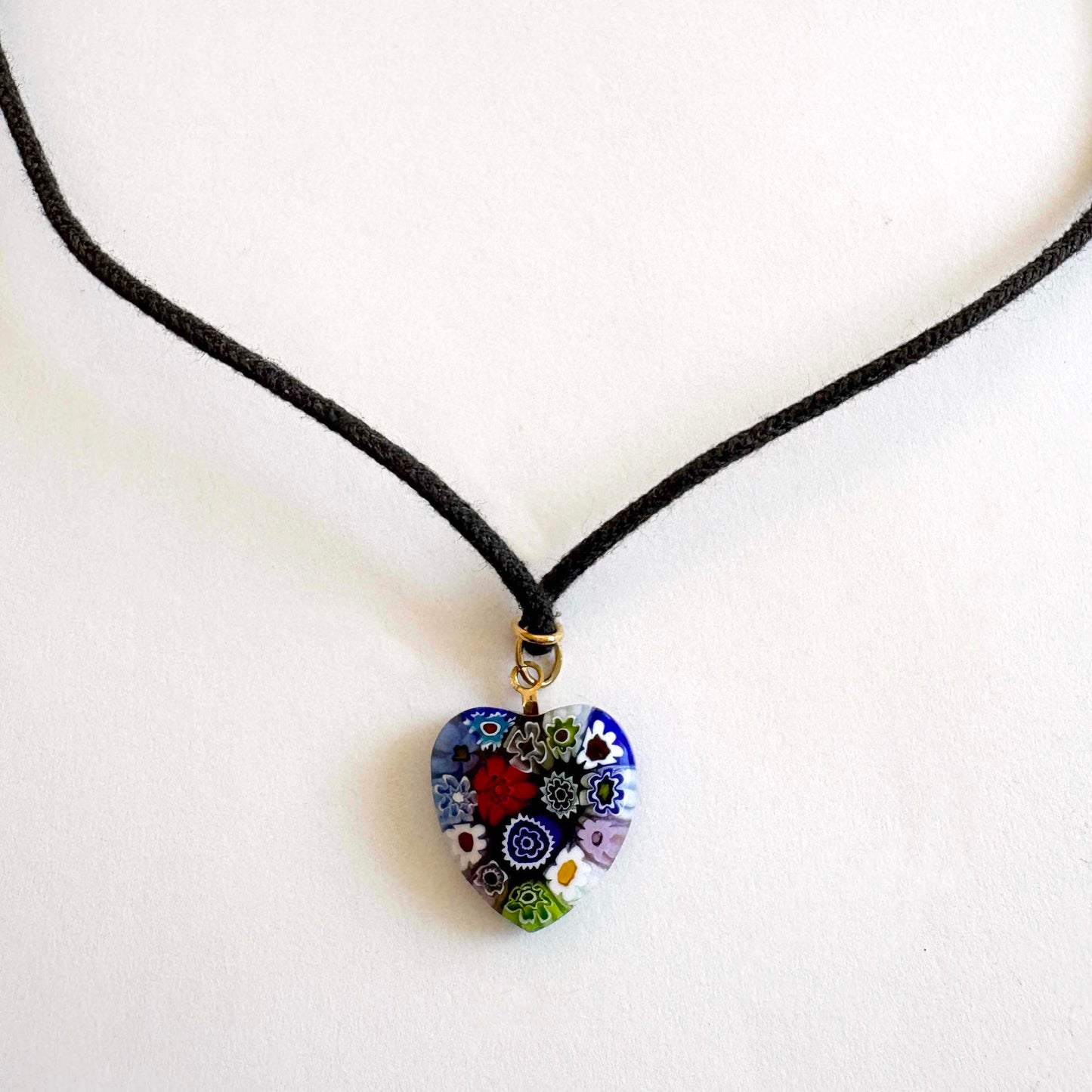 Murano millefiori glass heart necklace with multicolor floral pattern on black cord with gold-tone accents on white background