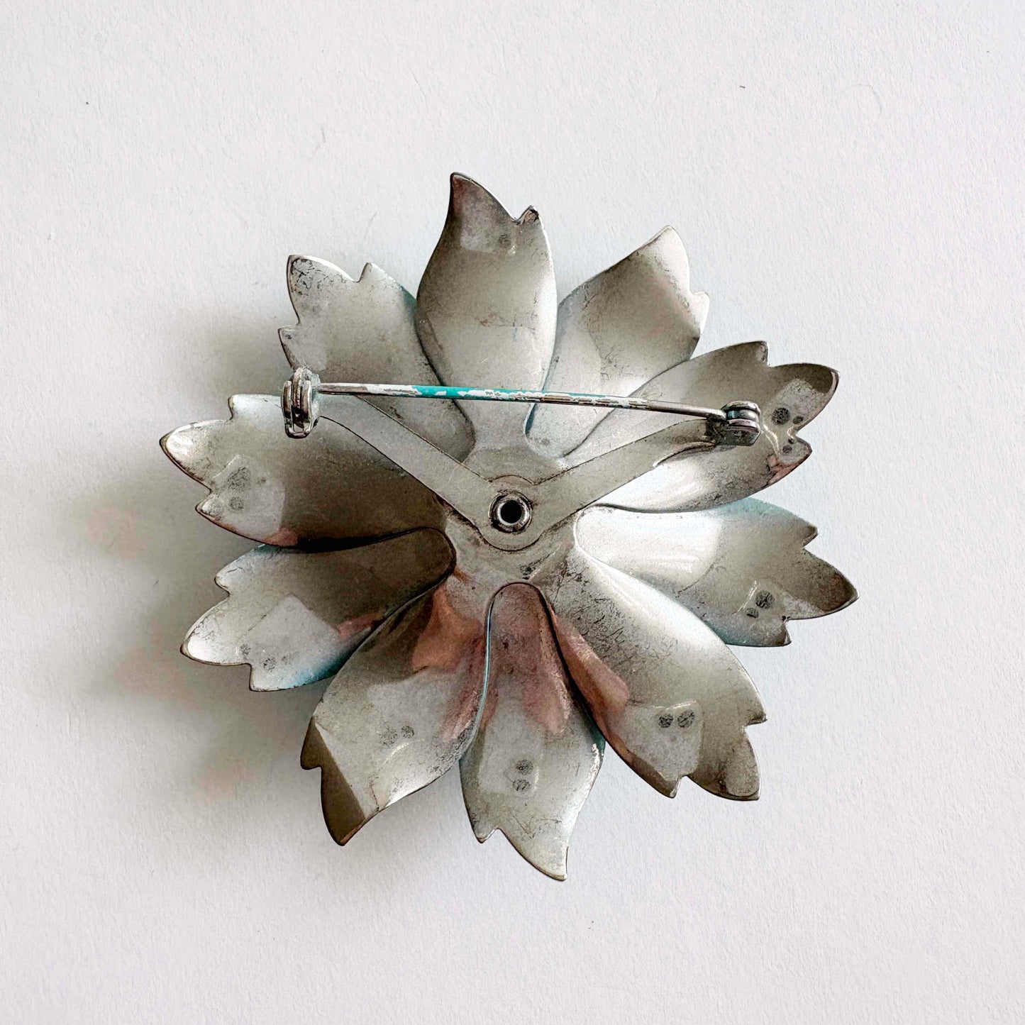 Metallic flower-shaped brooch on a white background