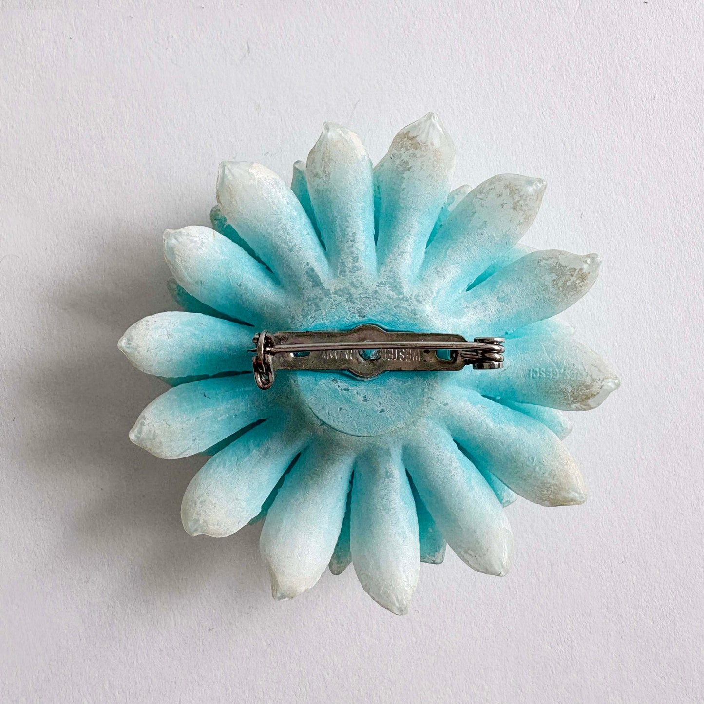 Light blue flower-shaped brooch on a white background