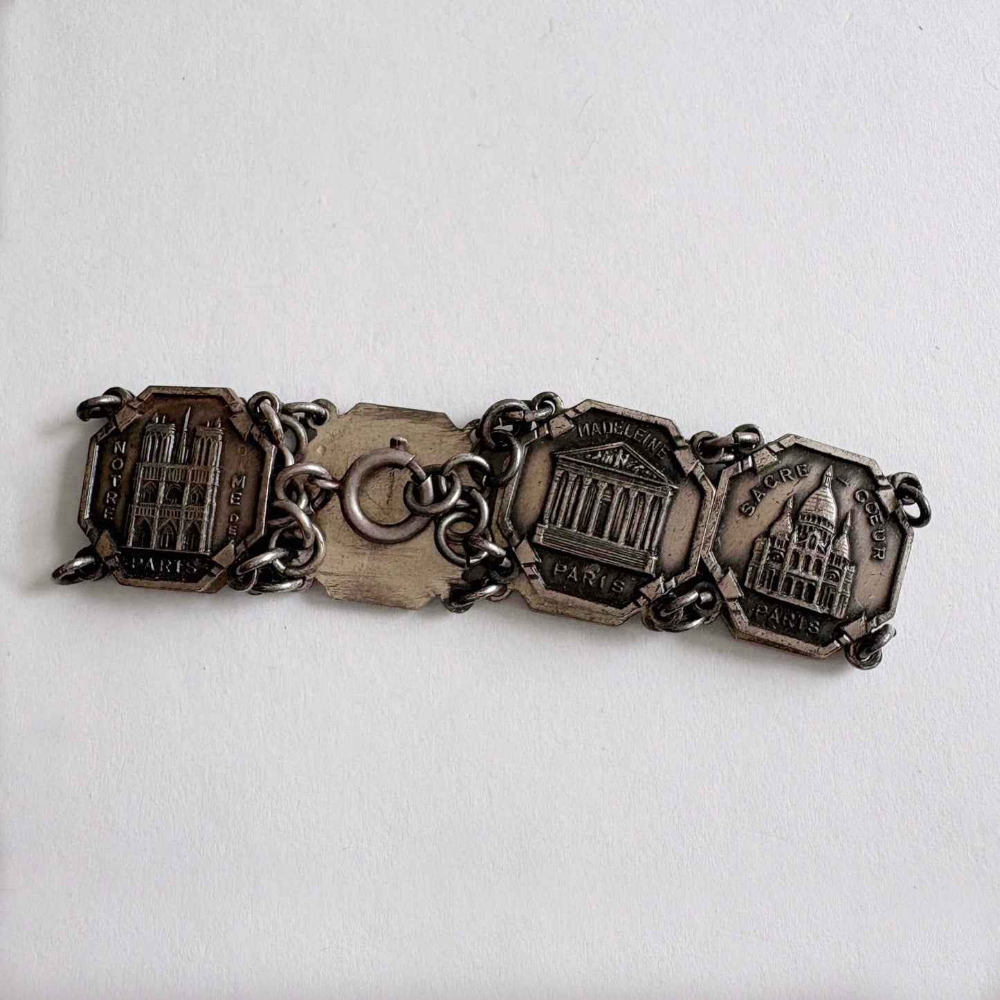Silver bracelet with various charms on a white background