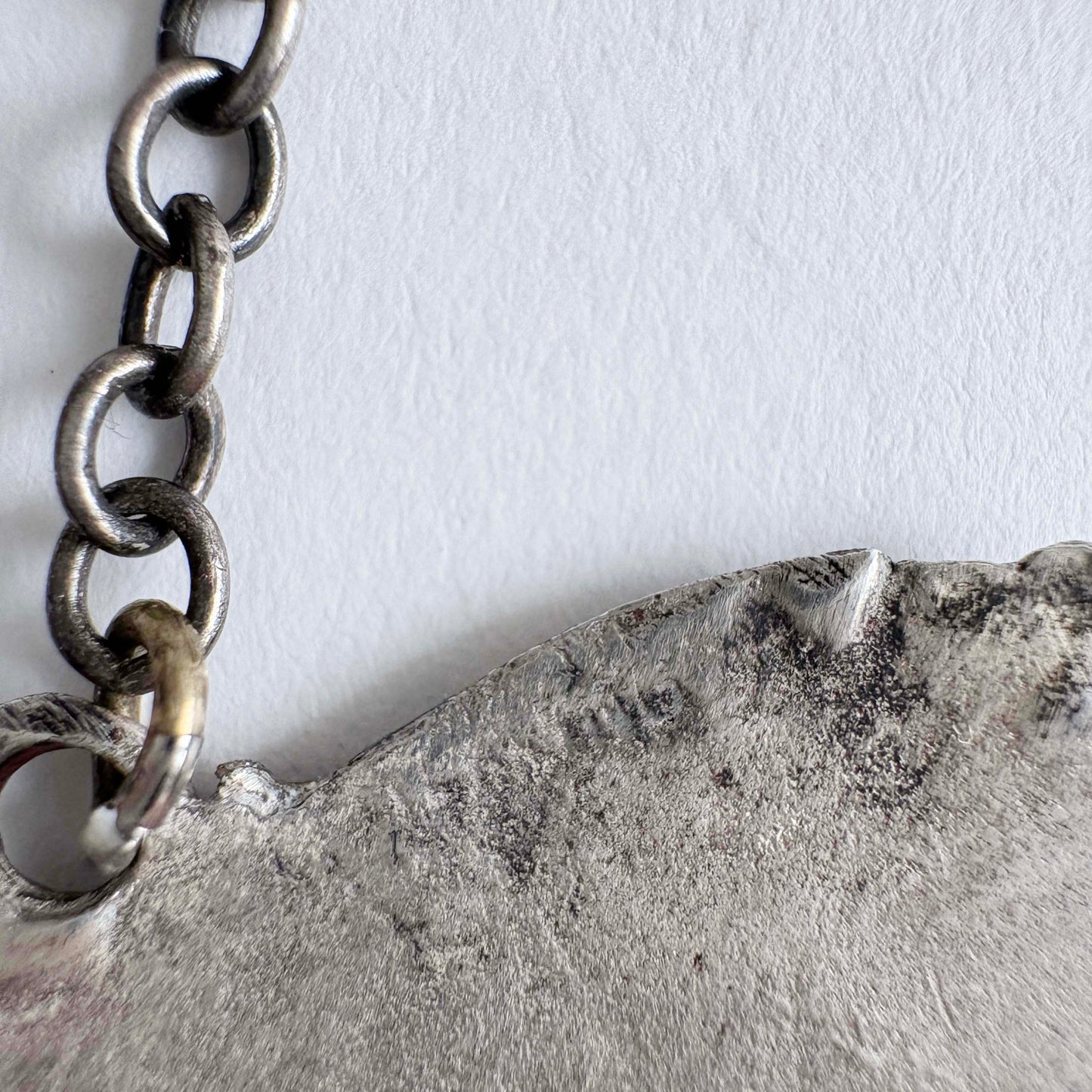Close-up of a sterling chain and textured surface on a light gray background