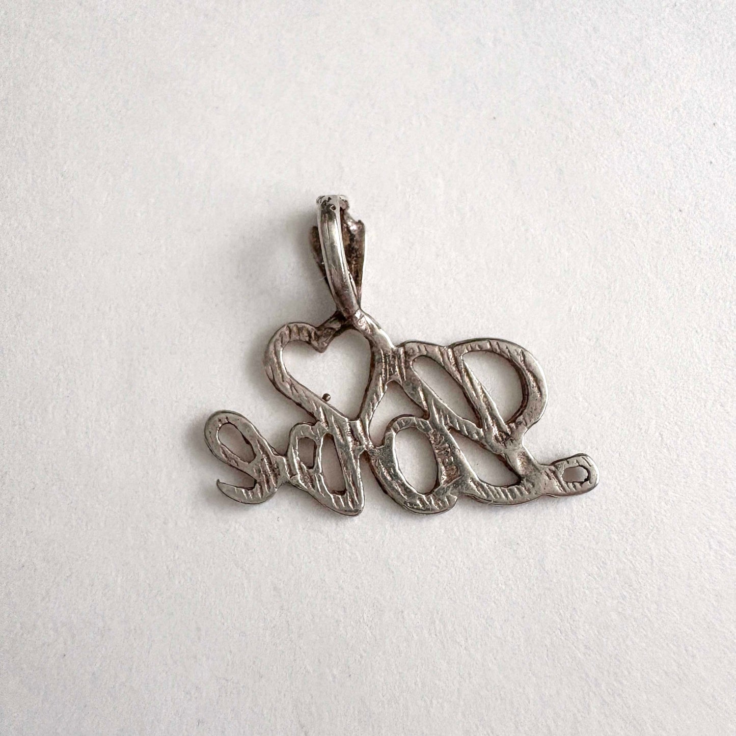 Silver pendant with 'love' on a white background