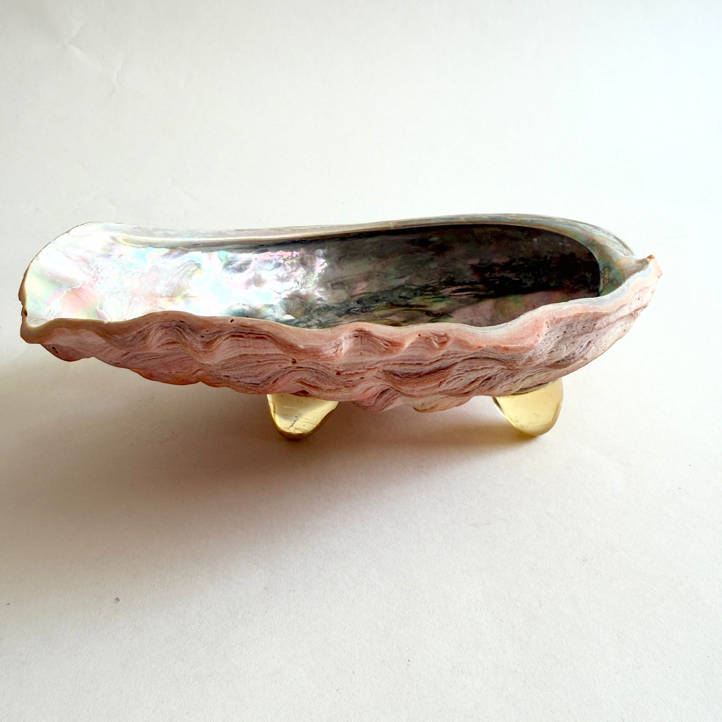 Side profile of the abalone shell bowl, showcasing the three vintage Lucite tripod feet and the floating silhouette.