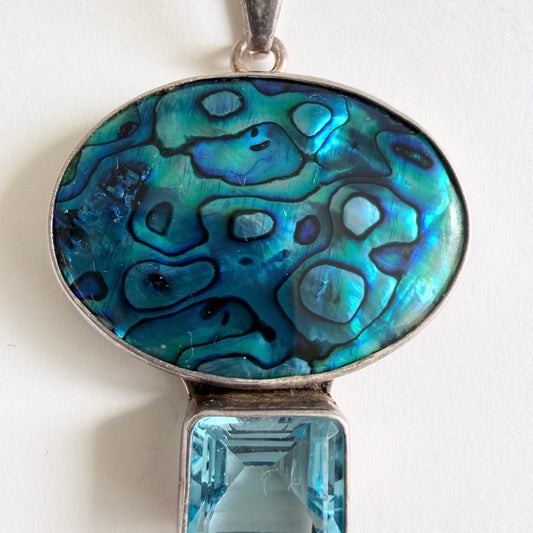 Close-up of the iridescent blue abalone shell showing deep oceanic teal and sapphire shifts in an organic pattern.