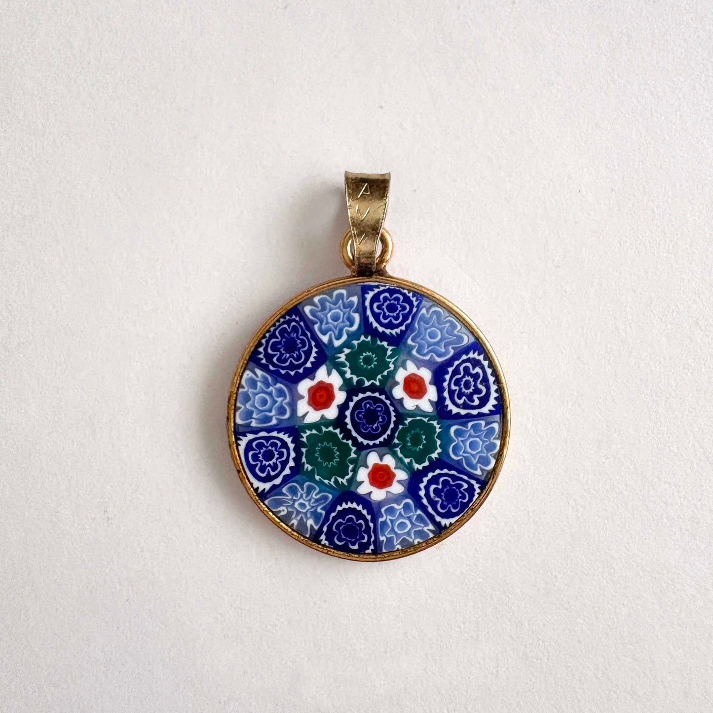 round floral Millefiori glass pendant with gold frame on a white background