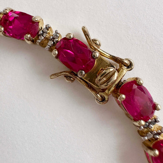 Gold bracelet with ruby gemstones on a white background