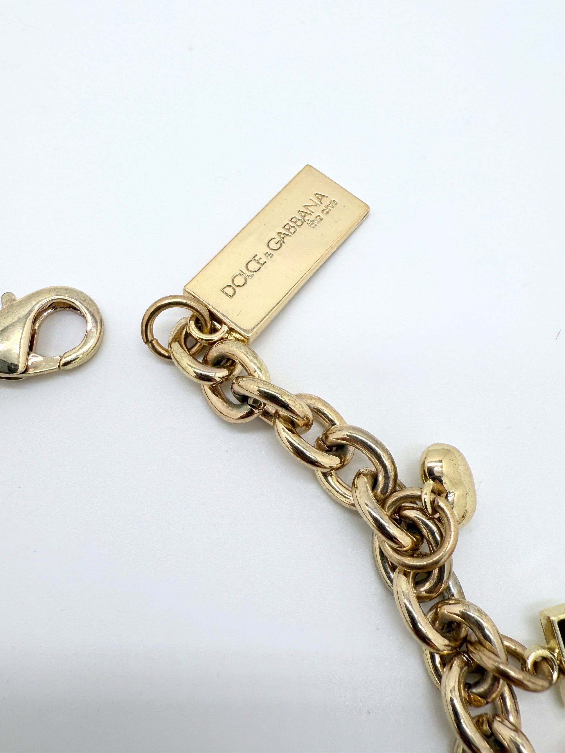Gold chain bracelet with a gold tag on a white background