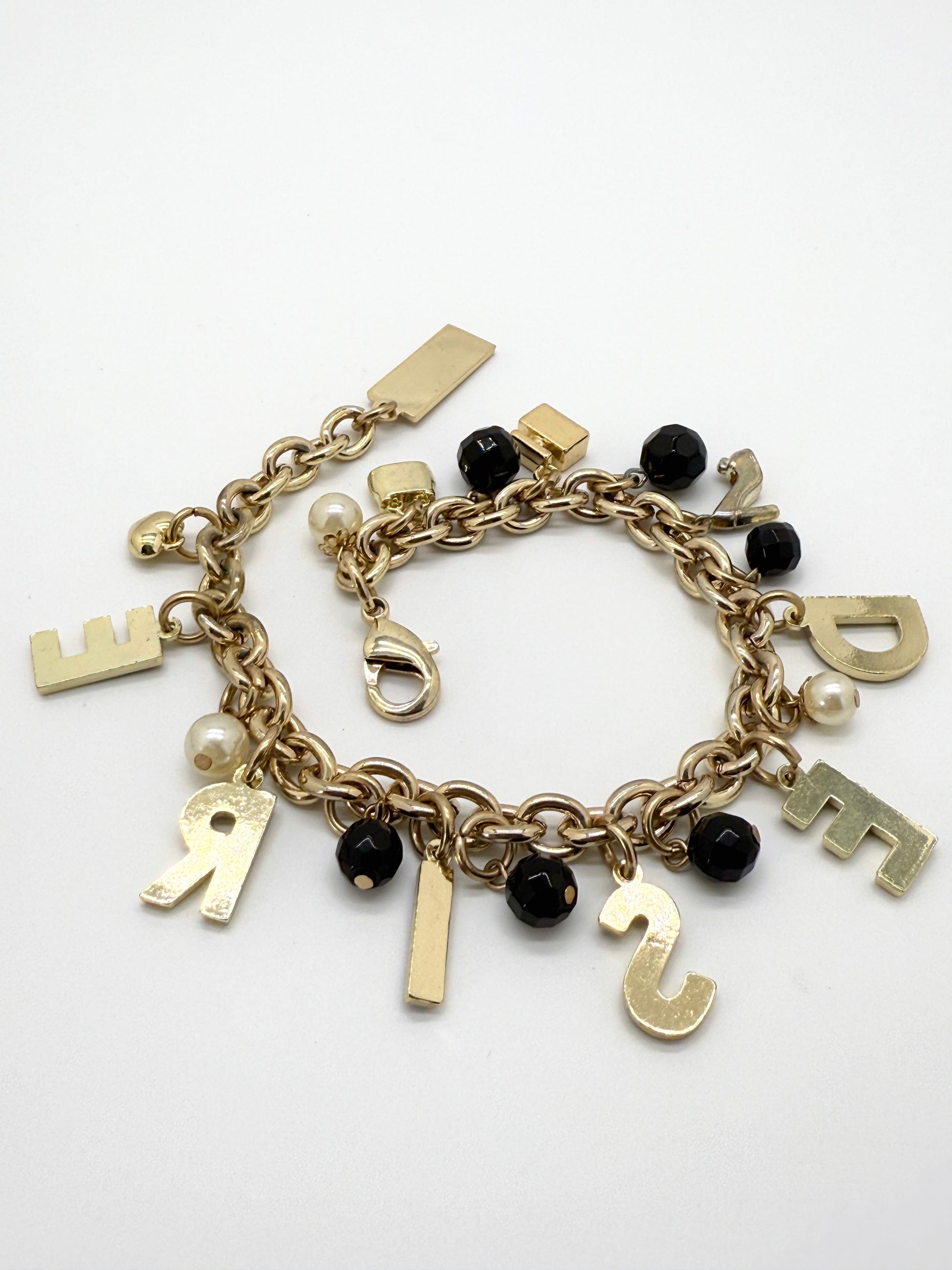 Gold charm bracelet with letters on a white background