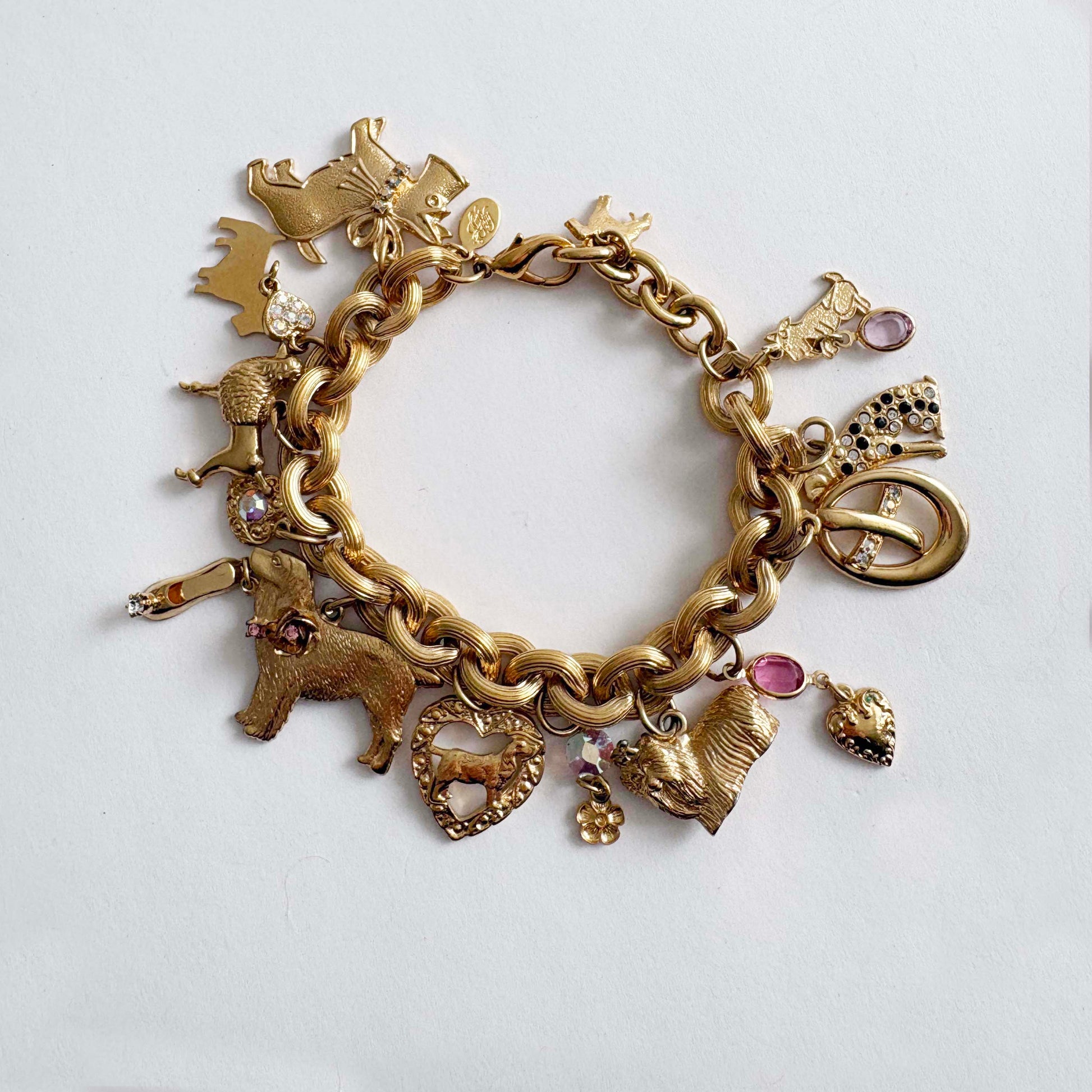 Vintage Kirk’s Folly gold-tone dog charm bracelet with rhinestones and whimsical charms on white background