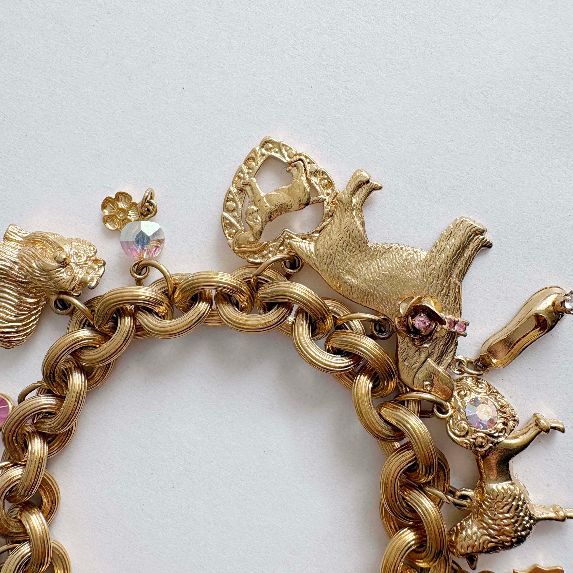 Vintage Kirk’s Folly gold-tone dog charm bracelet with rhinestones and whimsical charms on white background
