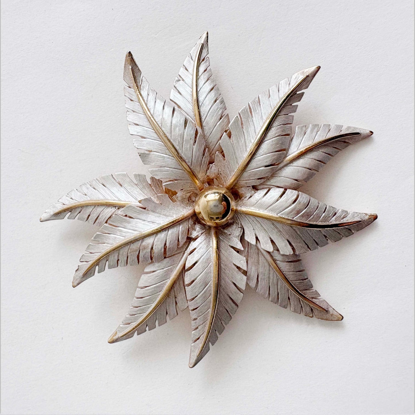 Vintage Lisa Jewels floral leaf brooch in silver and gold tones with layered metal leaves on white background