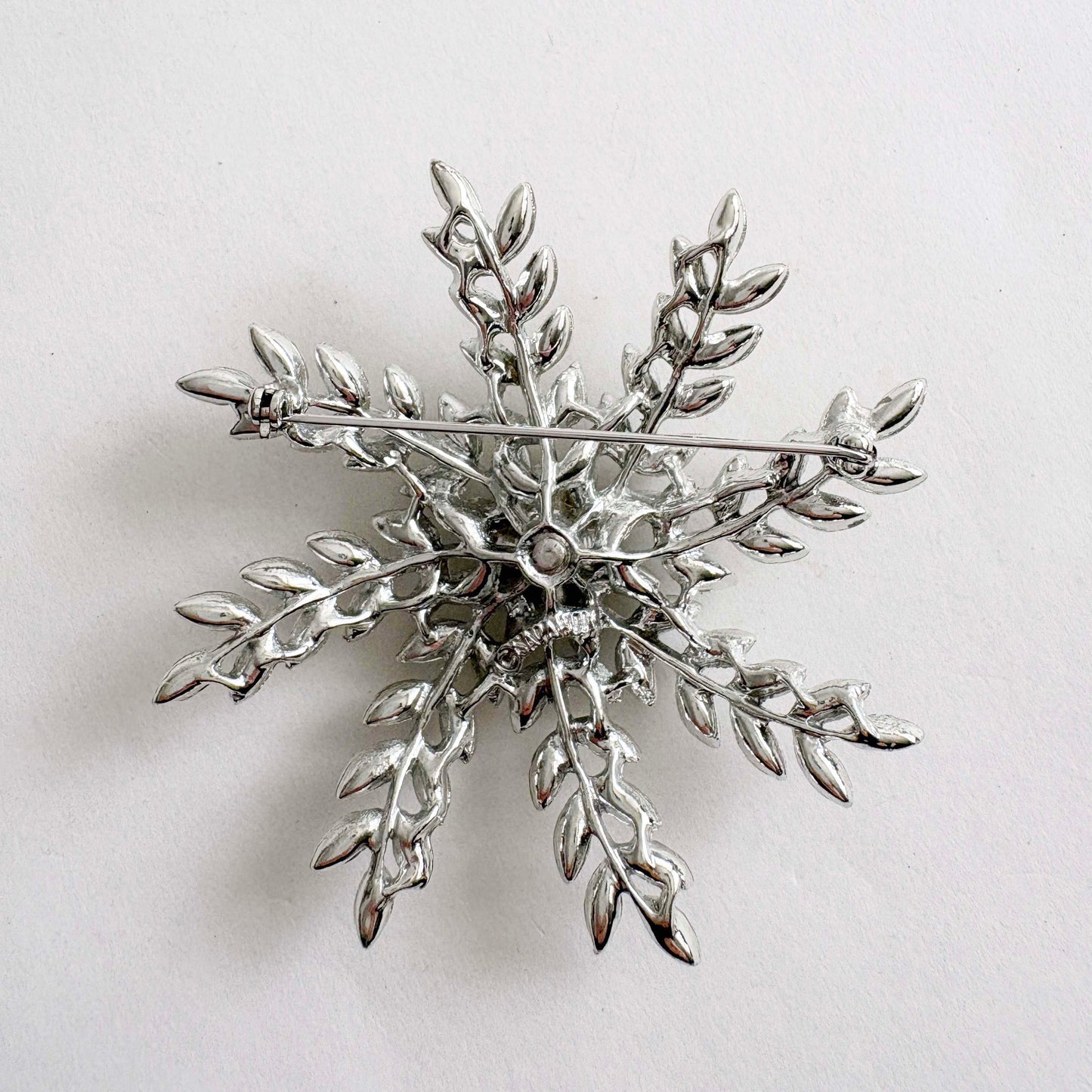 Silver snowflake brooch on a light gray background