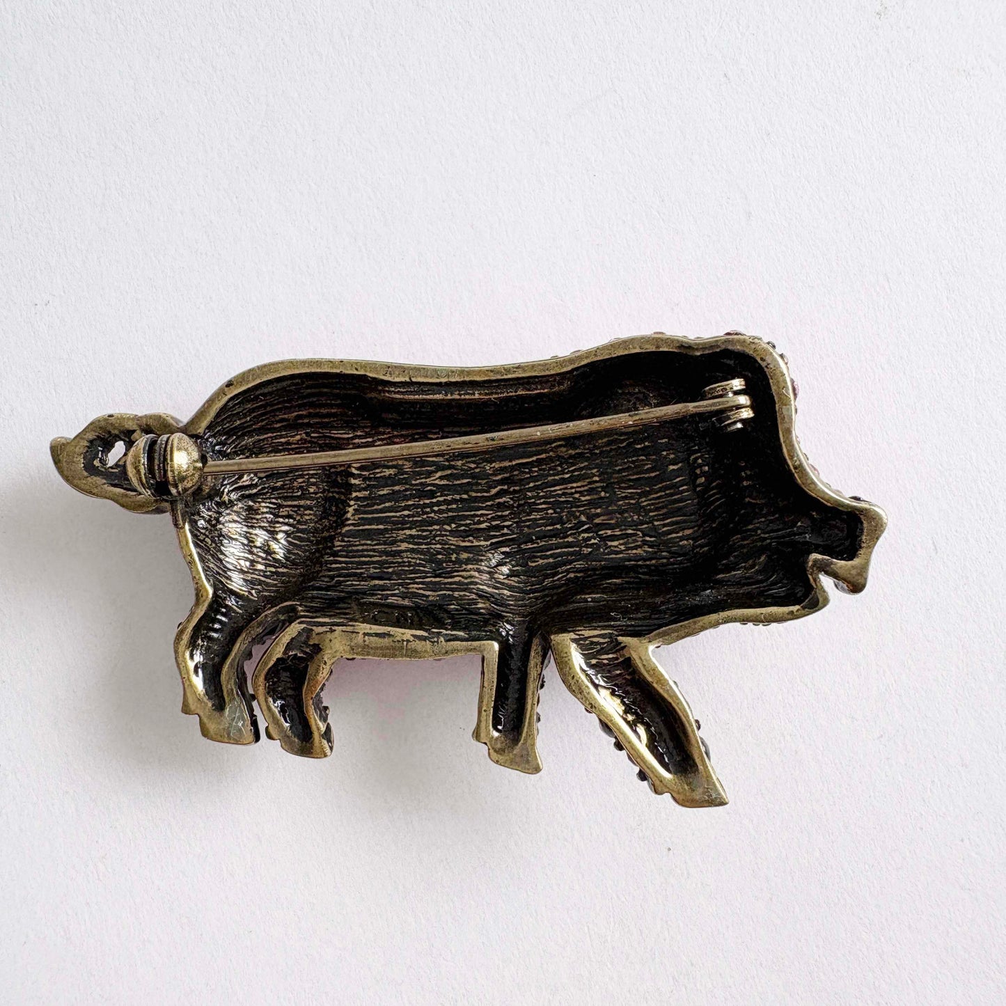 Bronze pig-shaped brooch on a white background