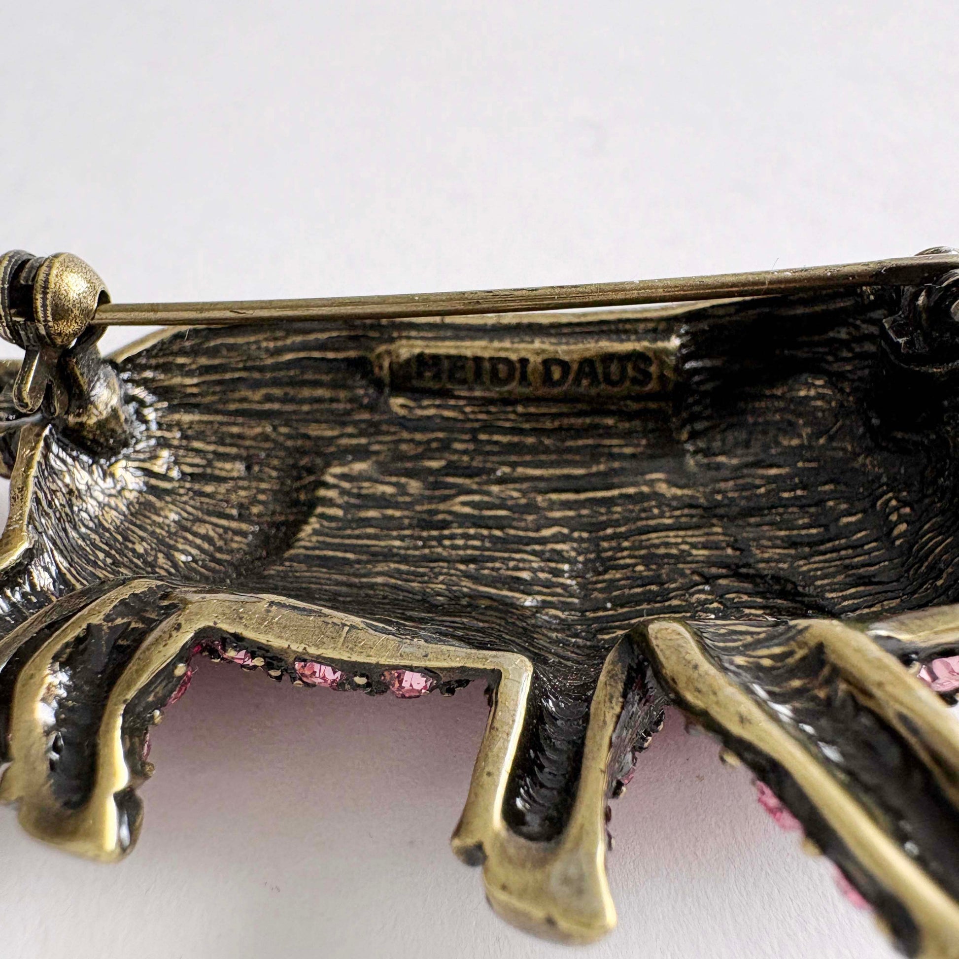 Close-up of a decorative brooch with 'Heidi Daus' branding.