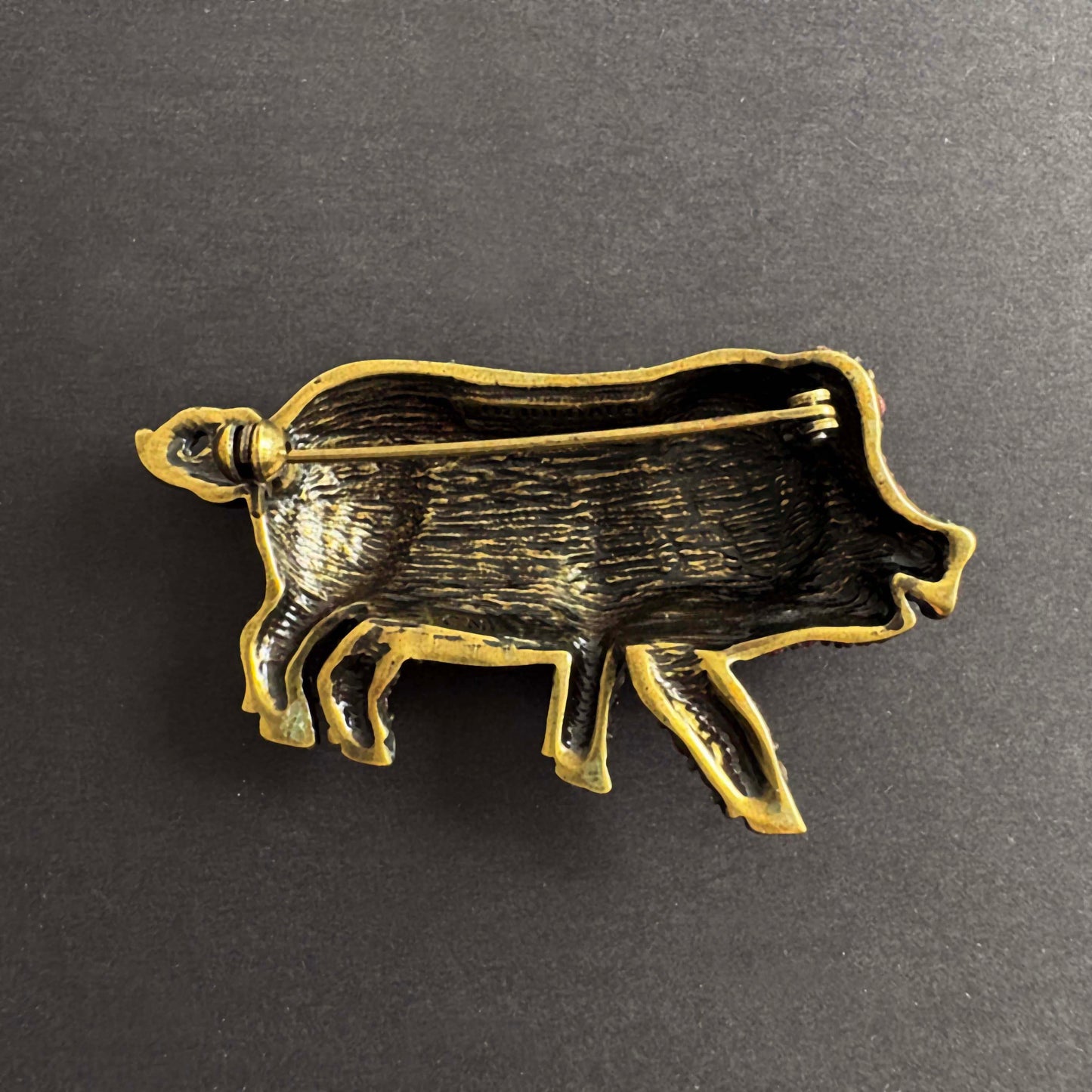 Brass pig-shaped object on a dark gray background