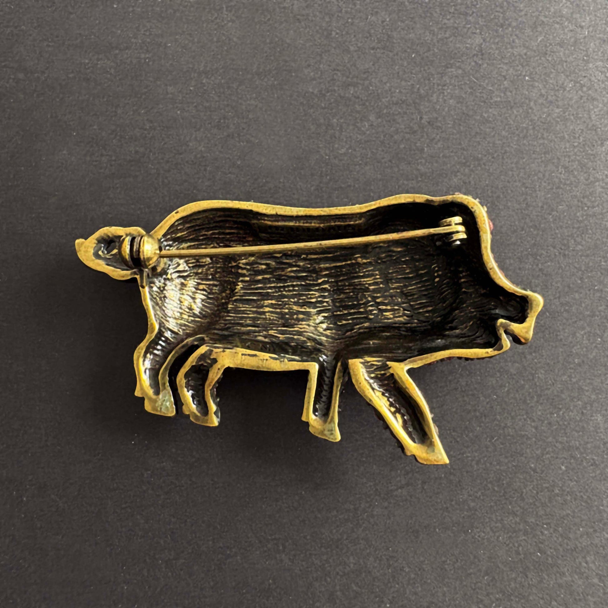 Brass pig-shaped object on a dark gray background