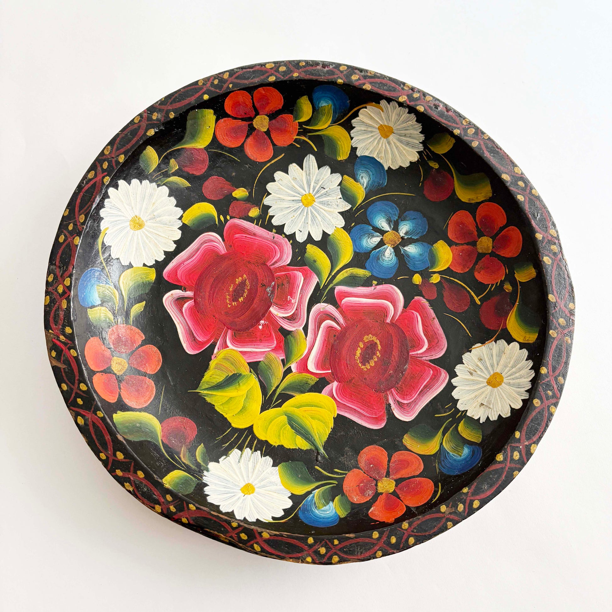 Vintage hand-painted Mexican wooden batea tray with colorful floral folk art on a black background, round decorative bowl
