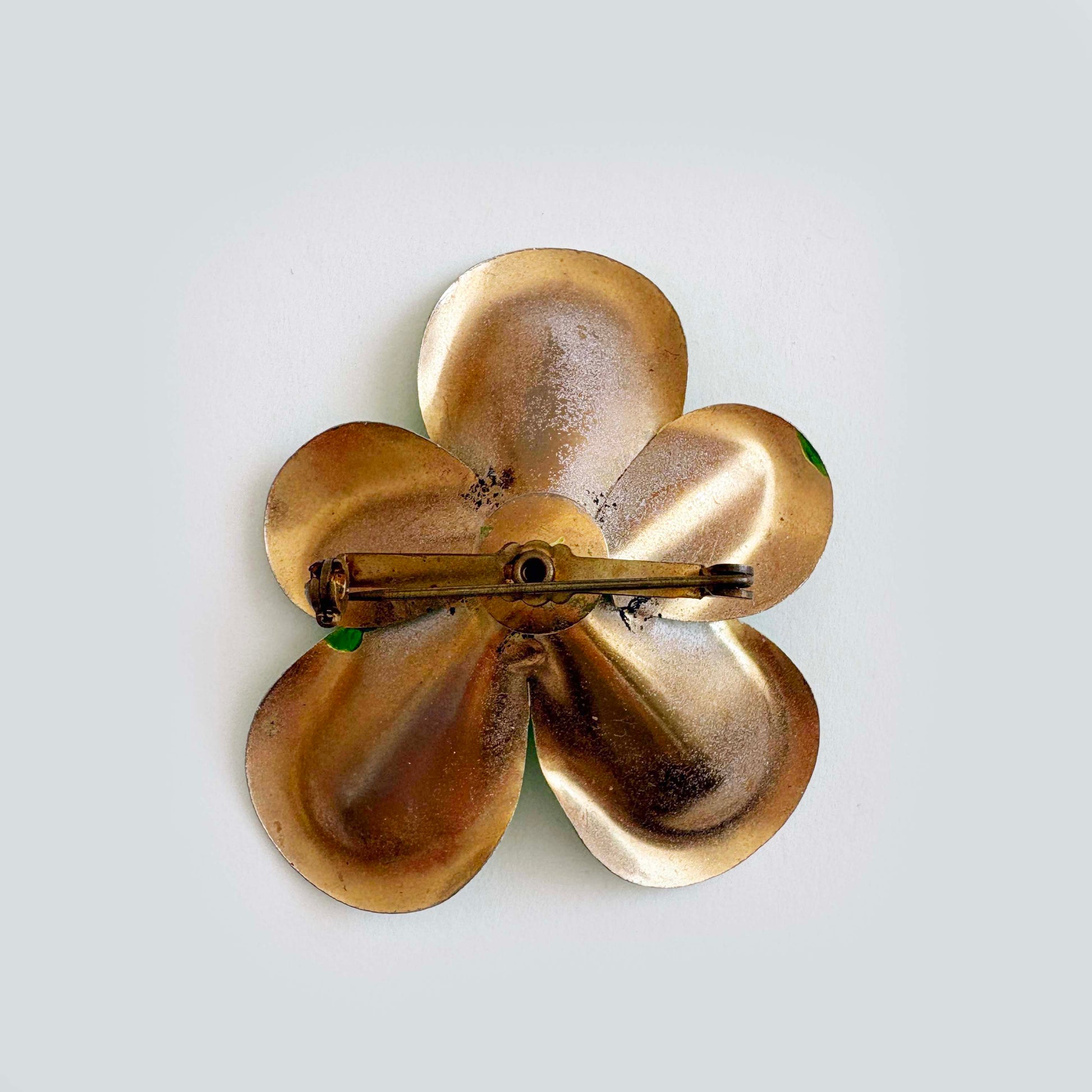 Gold flower-shaped brooch on a light gray background