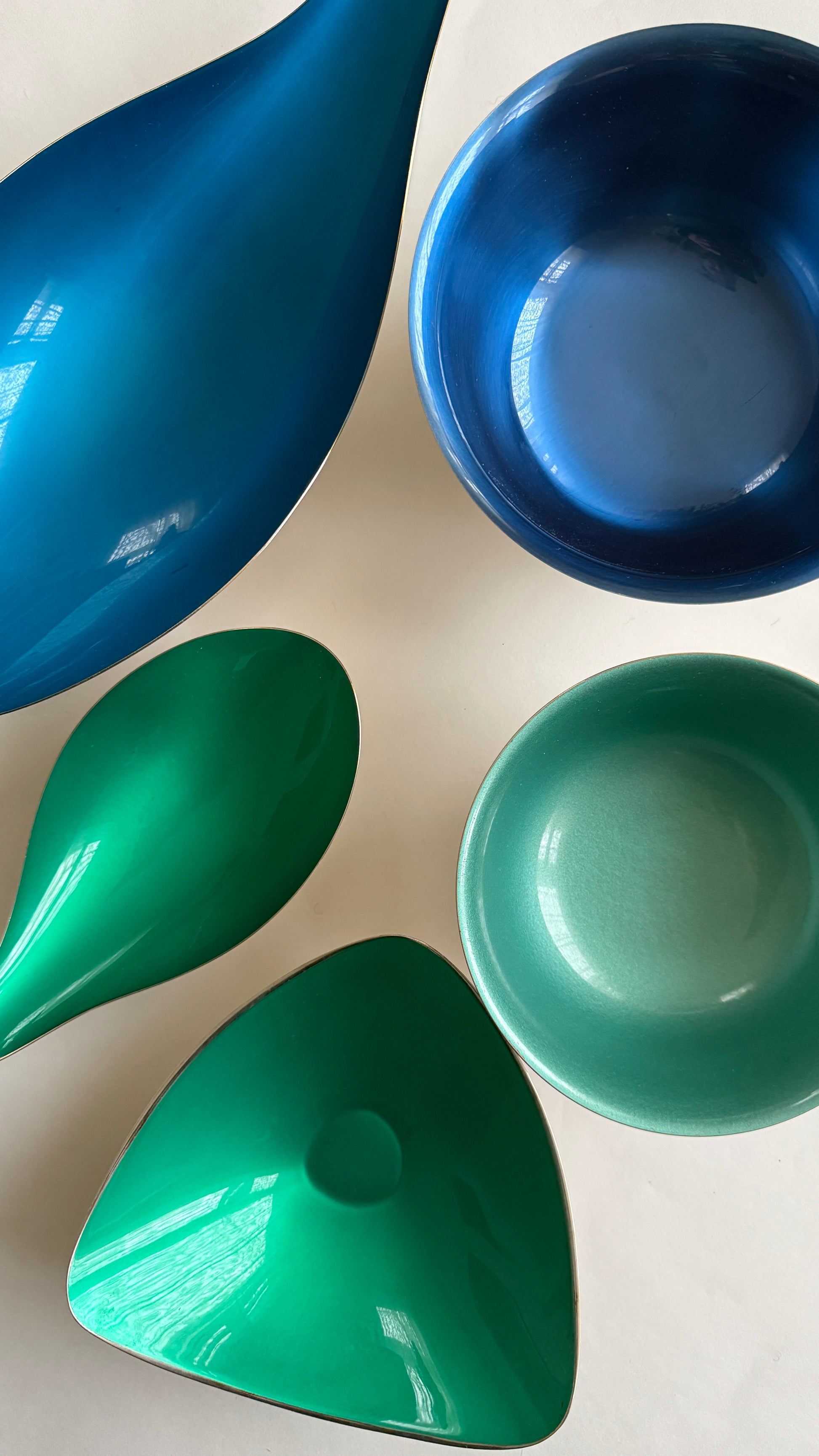 Set of blue and green enamel bowls on a light background