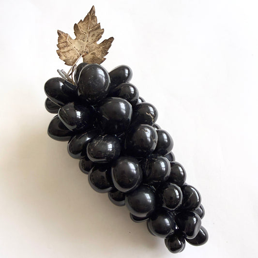 Decorative black grape bunch with a silver leaf on a white background