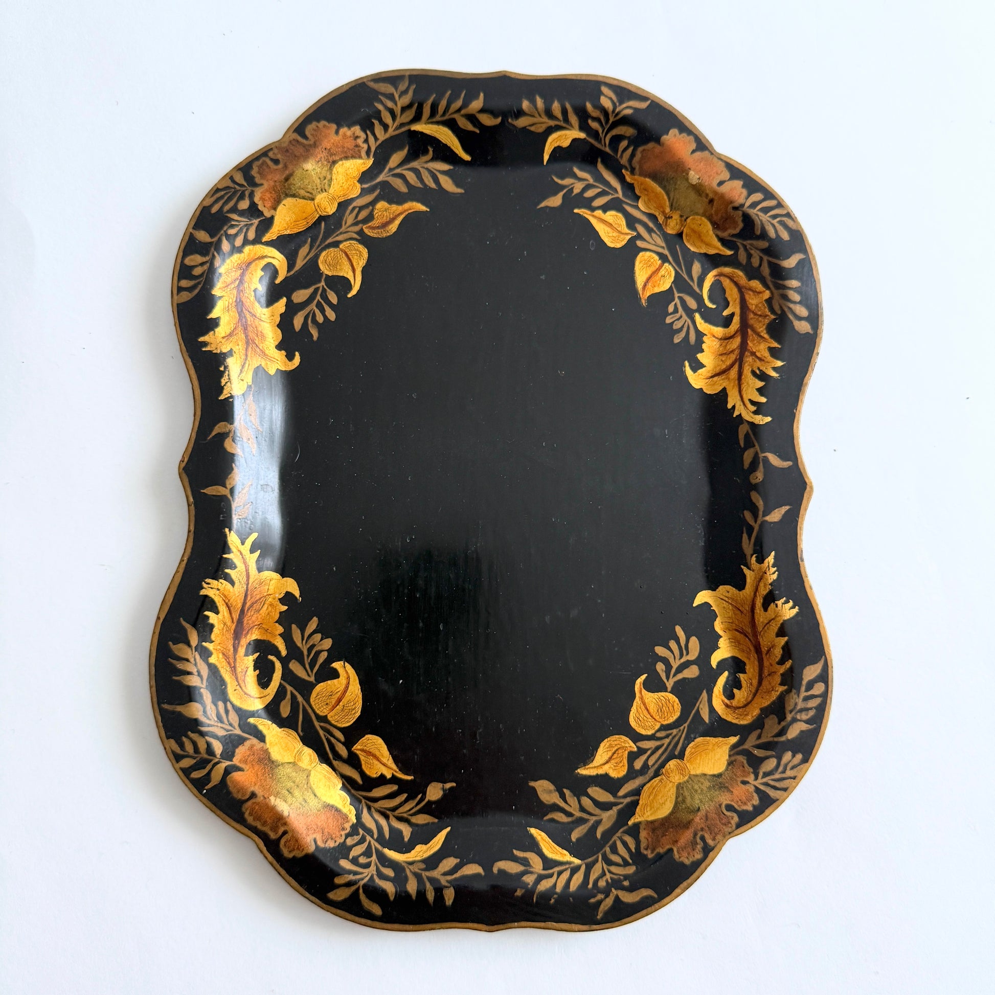 Decorative black plate with gold leaf patterns on a white background