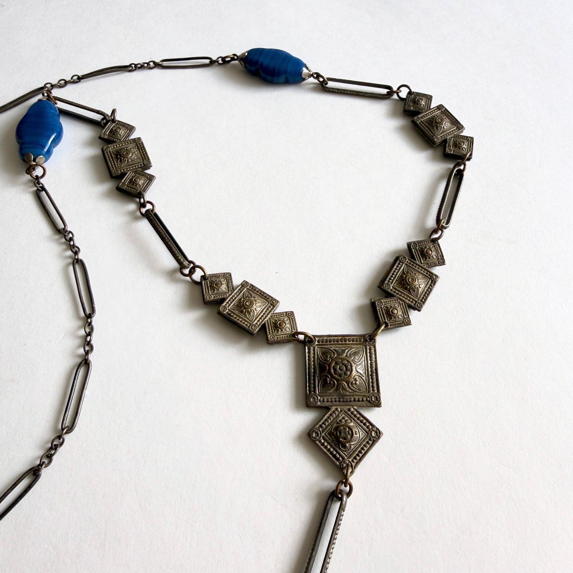 Vintage Czech Art Deco sautoir necklace with molded blue glass drop pendant and geometric stamped metal panels, circa 1920s–1930s.