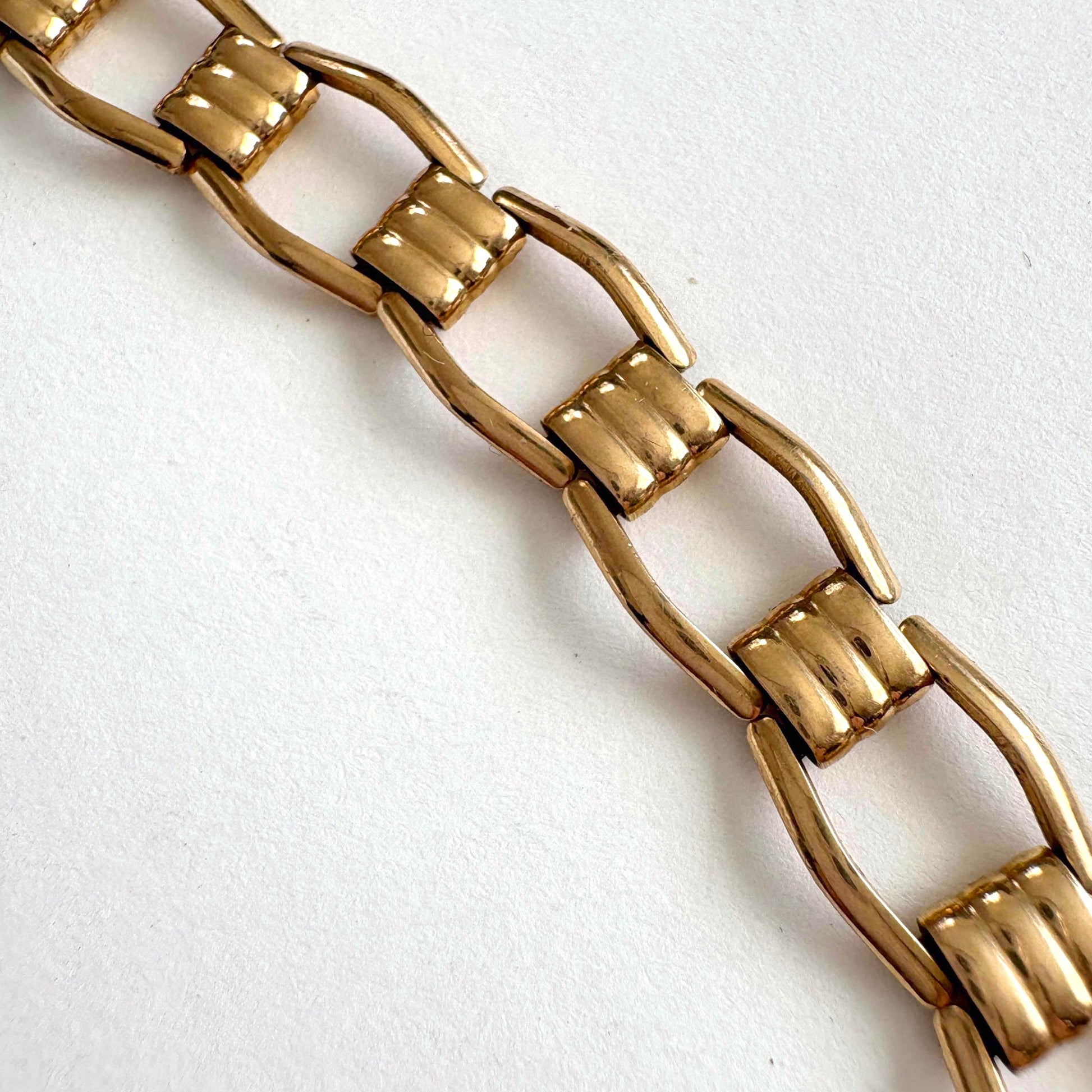 Close-up of a Kreisler gold tone chain bracelet on a white background
