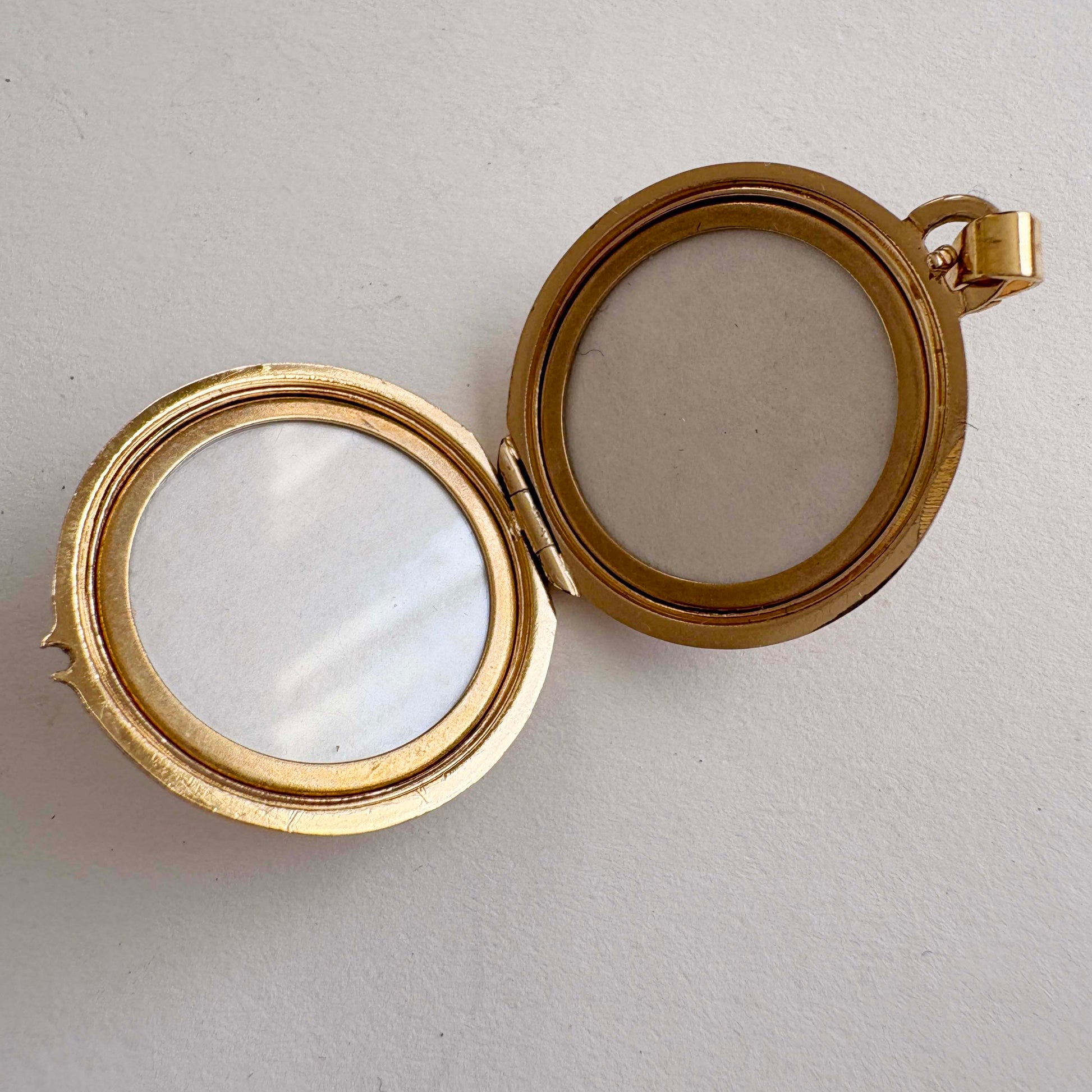 Gold locket with two circular compartments on a light gray background