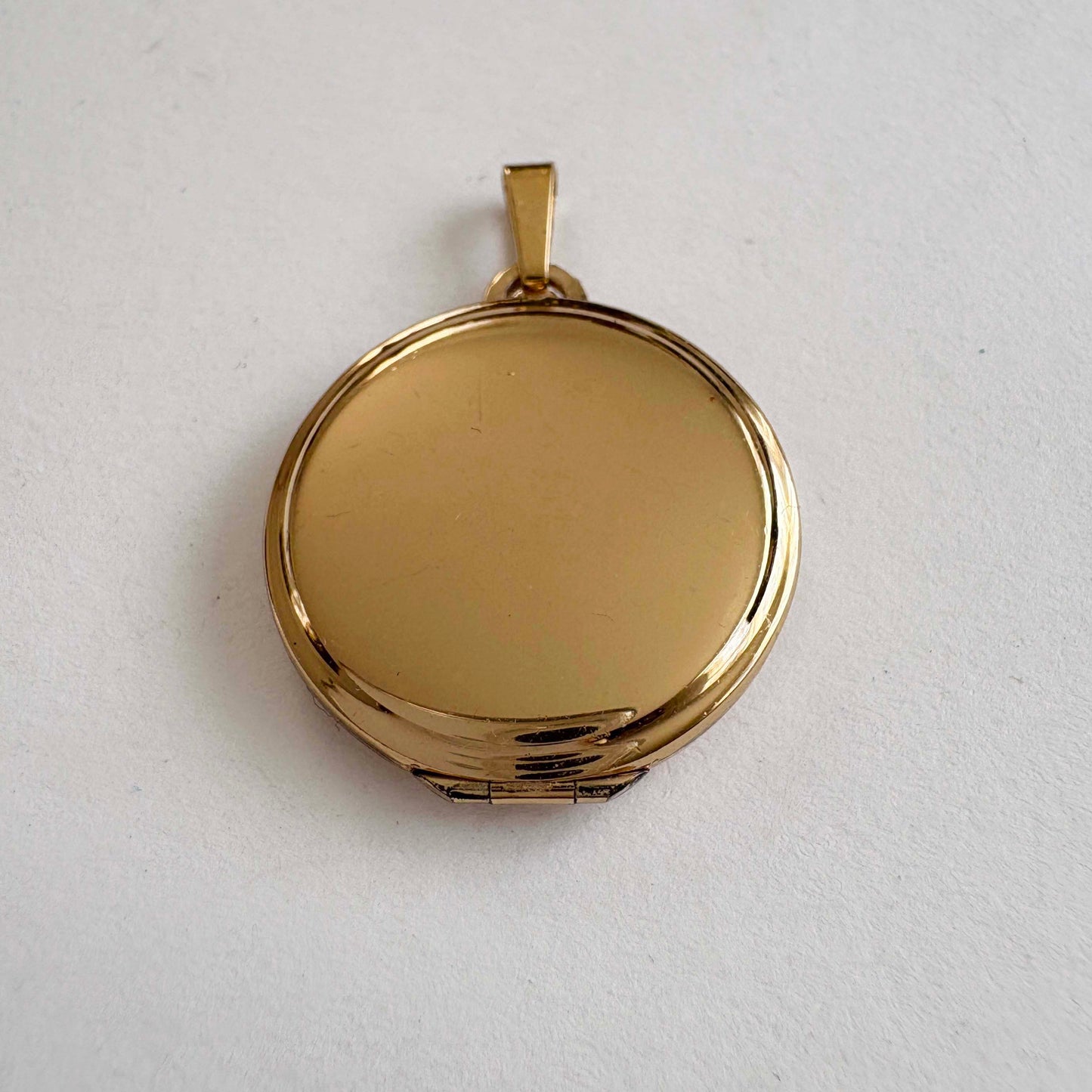 Vintage Monet gold-tone round locket pendant, smooth polished finish, 1980s costume jewelry on white background