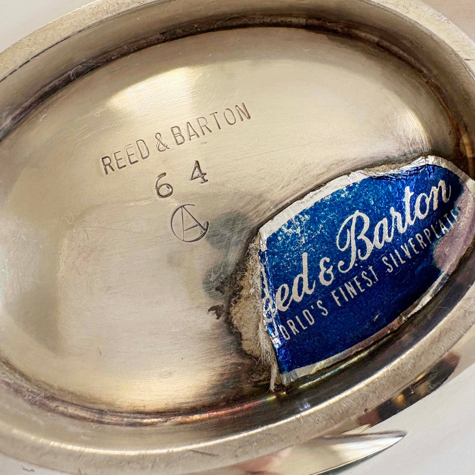 Close-up of a silver bowl with 'Reed & Barton' branding and a label.