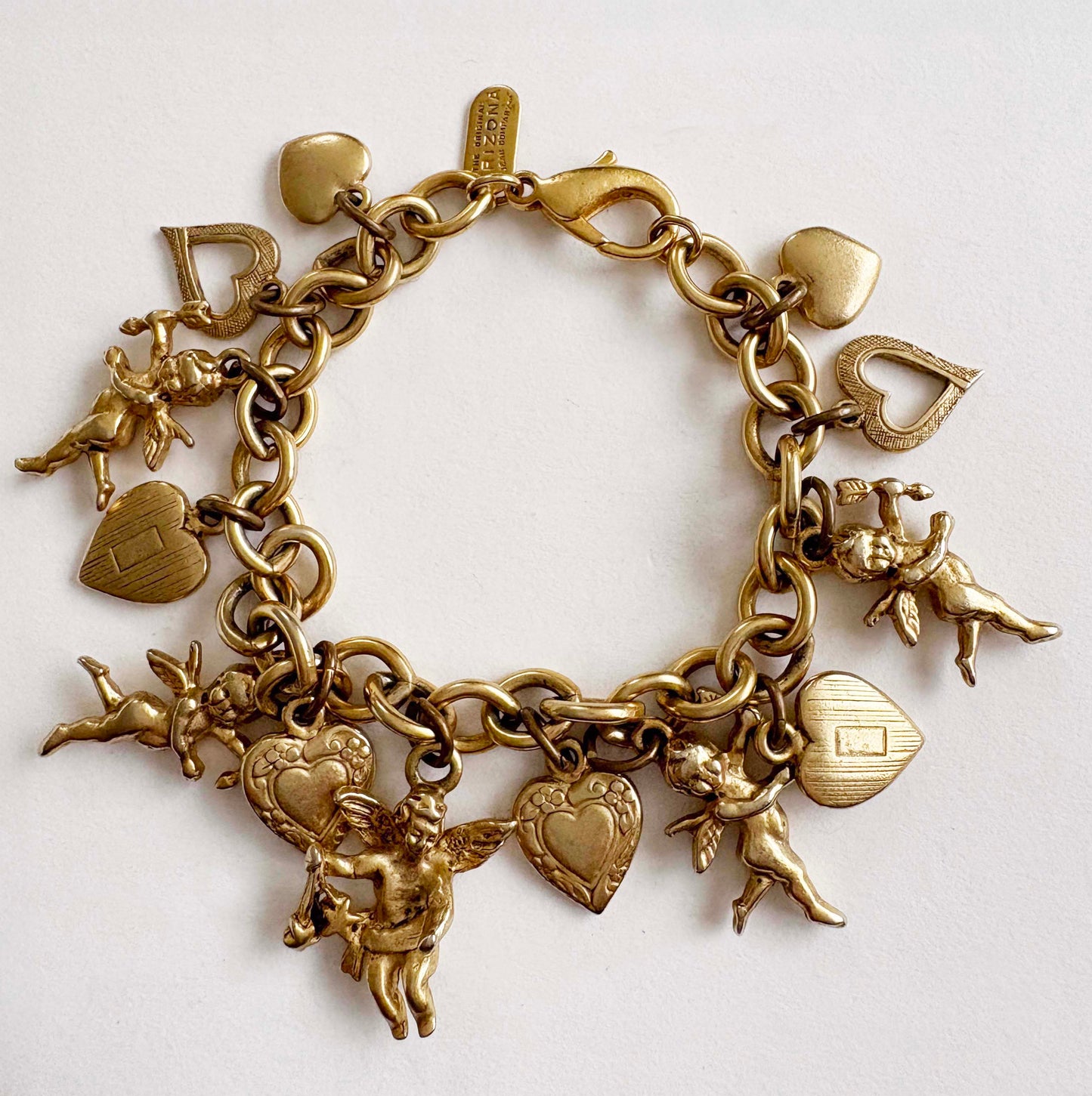 Gold charm bracelet with heart and angel charms by The Original Arizona Jean Company on a white background