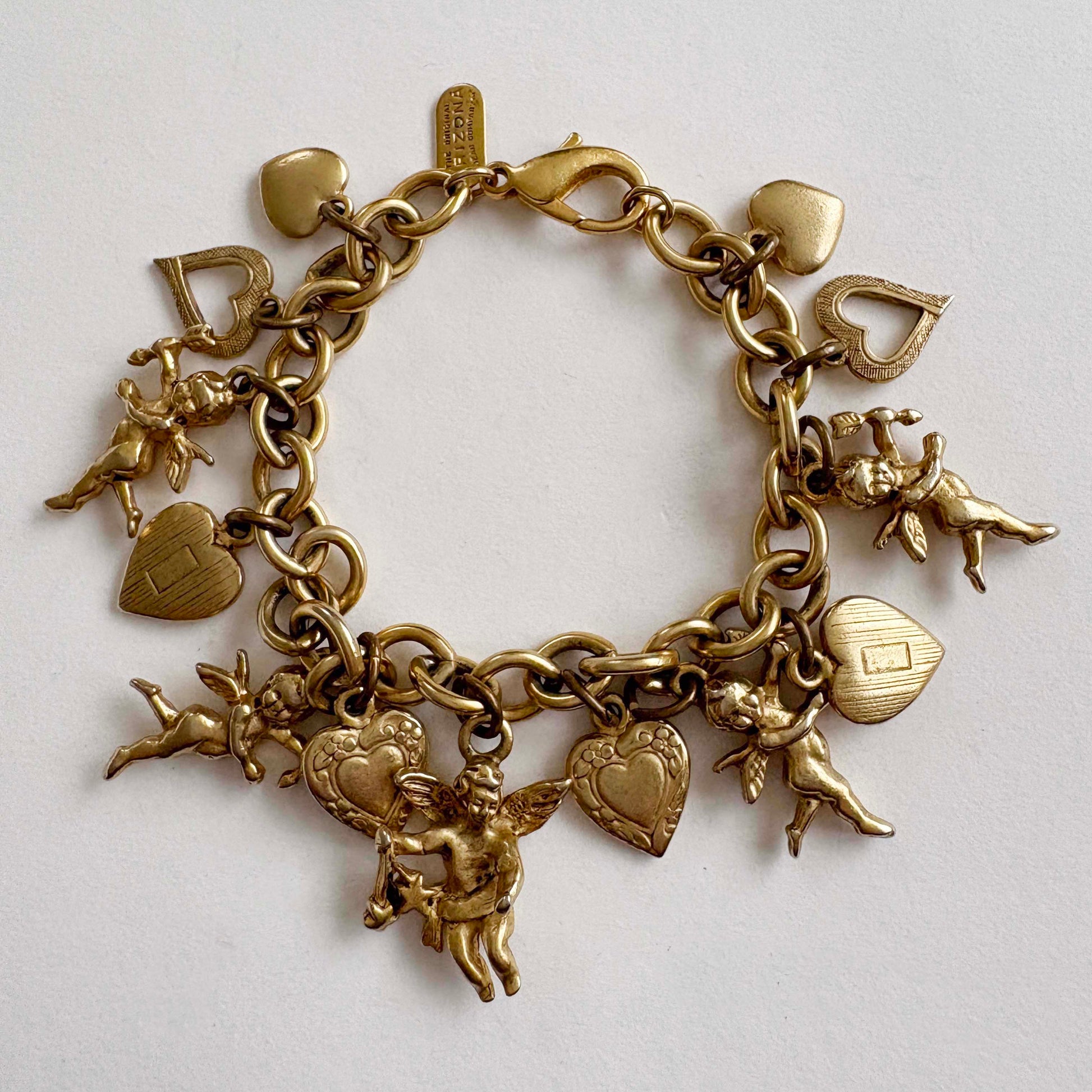 Gold charm bracelet with various charms on a light gray background