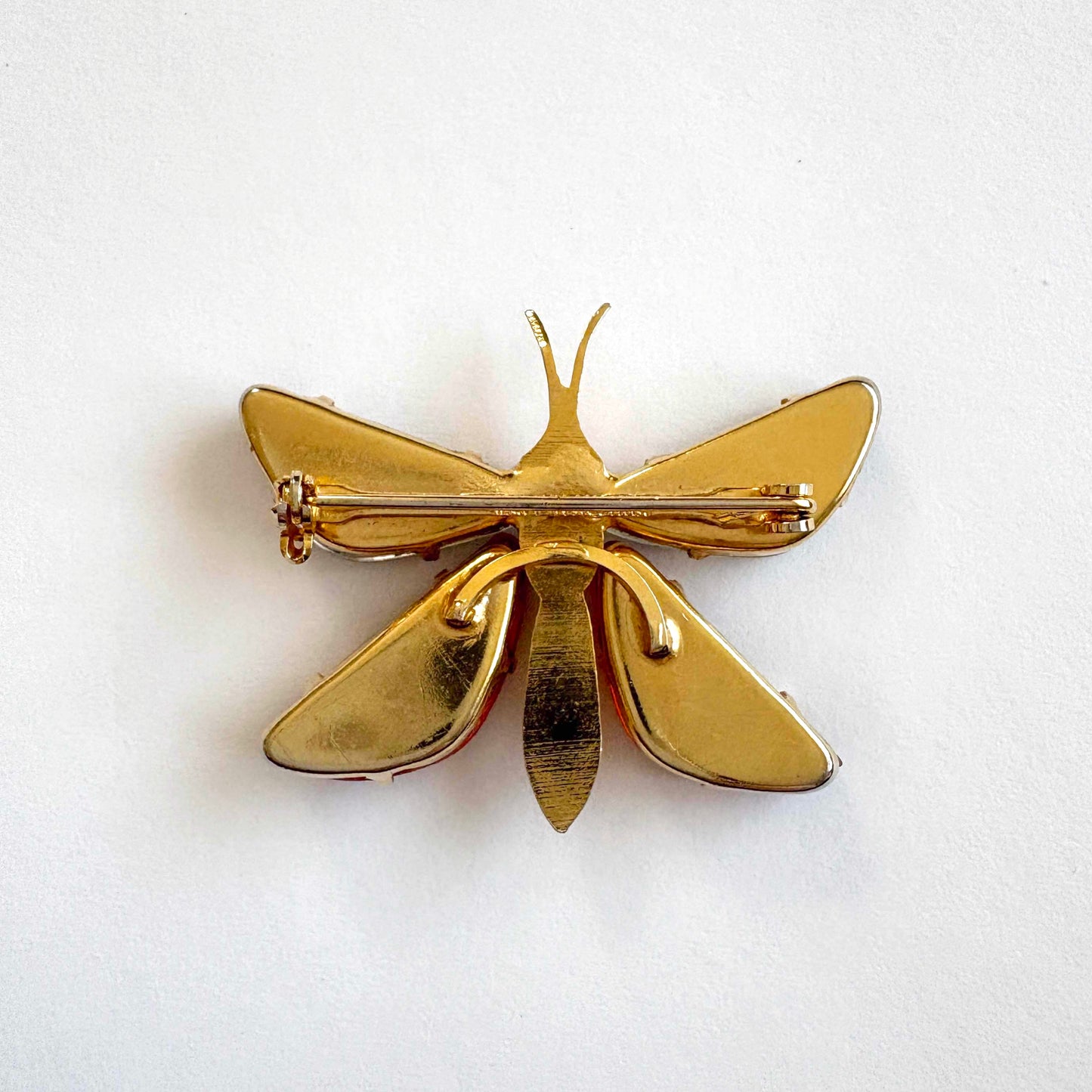 Gold butterfly-shaped brooch on a white background