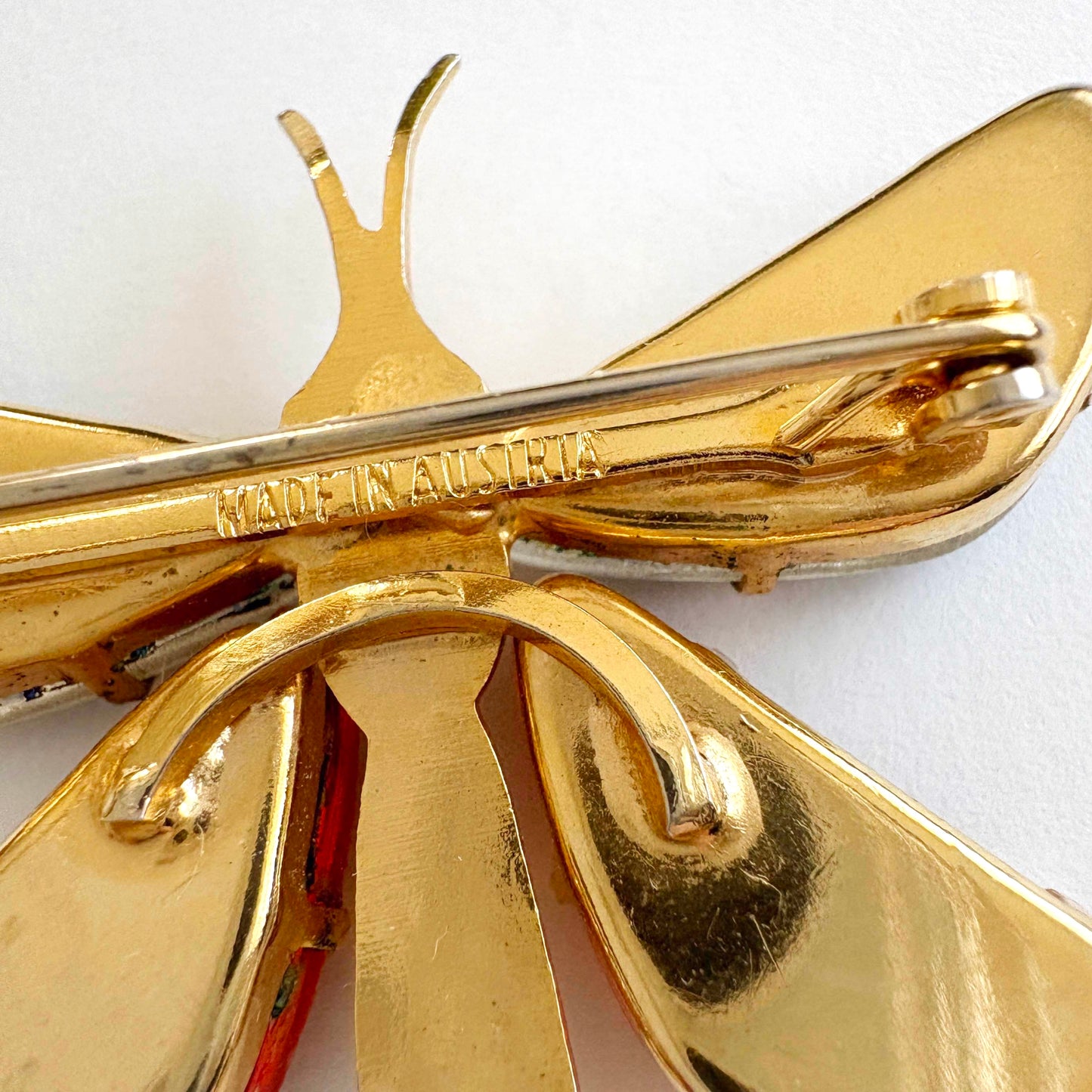 Gold butterfly brooch with 'MADE IN AUSTRIA' engraving on a white background