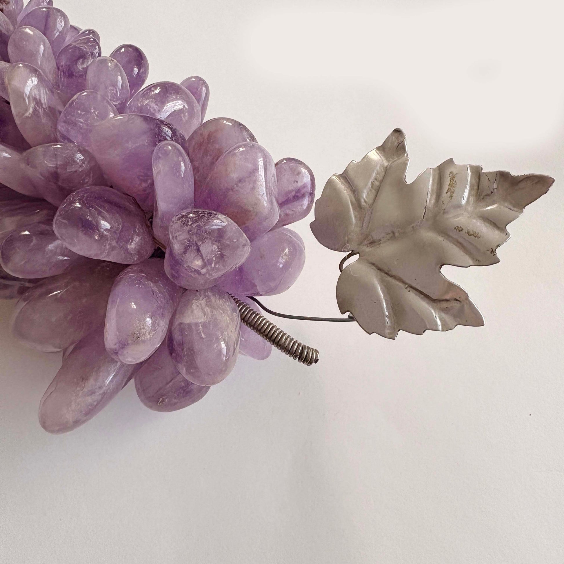 Amethyst stone grapes with a silver leaf on a white background
