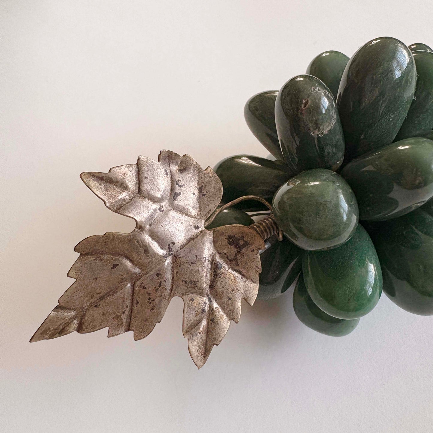 Silver leaf with green stones on a white background