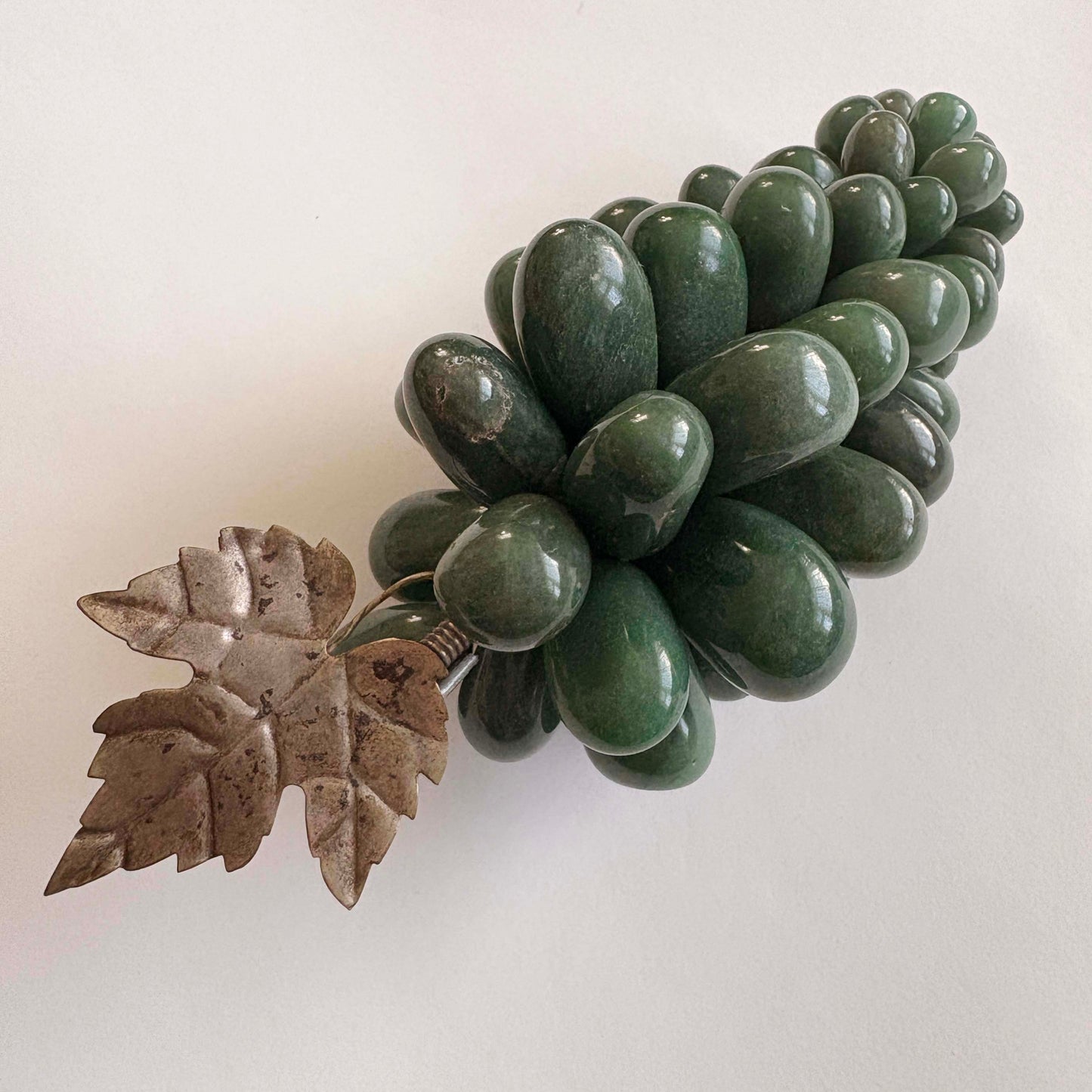 Decorative green stone grapes and a leaf on a white background