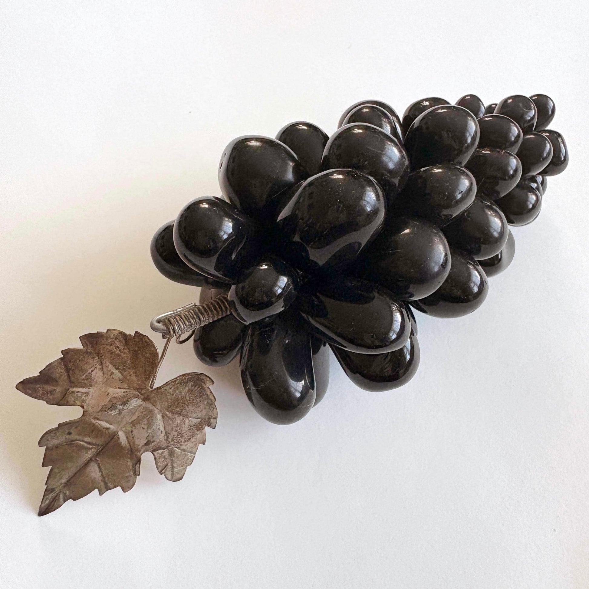 Black grape cluster with a silver leaf on a white background