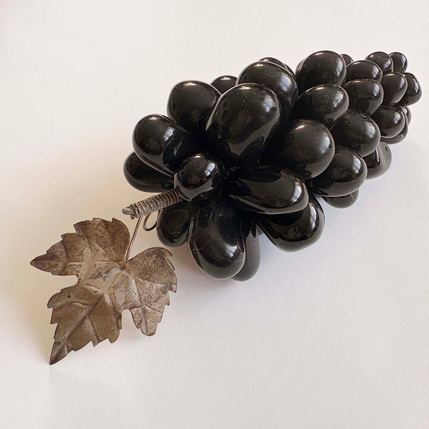 Black grape cluster with a leaf on a white background