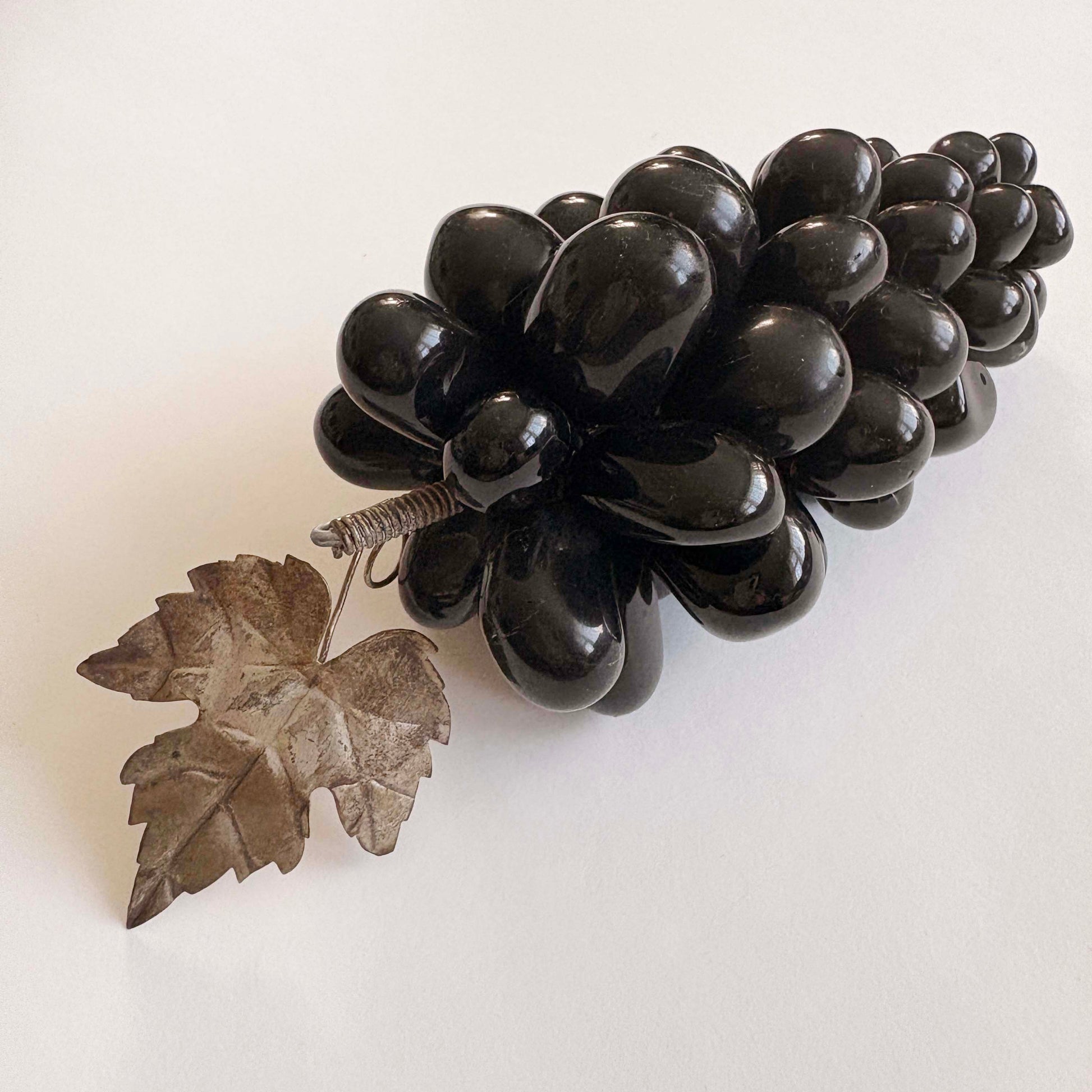 Black grape cluster with a leaf on a white background