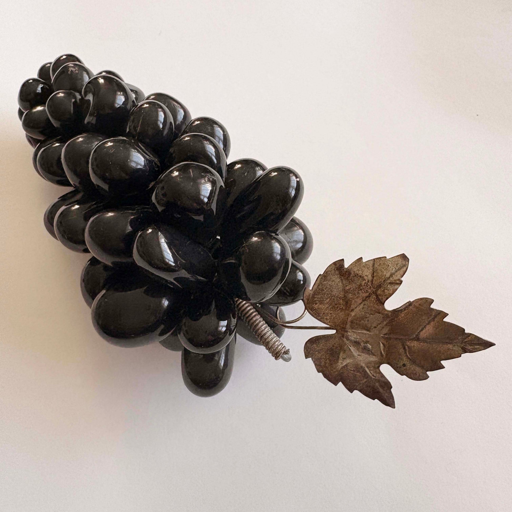Black decorative grapes with a leaf on a white background