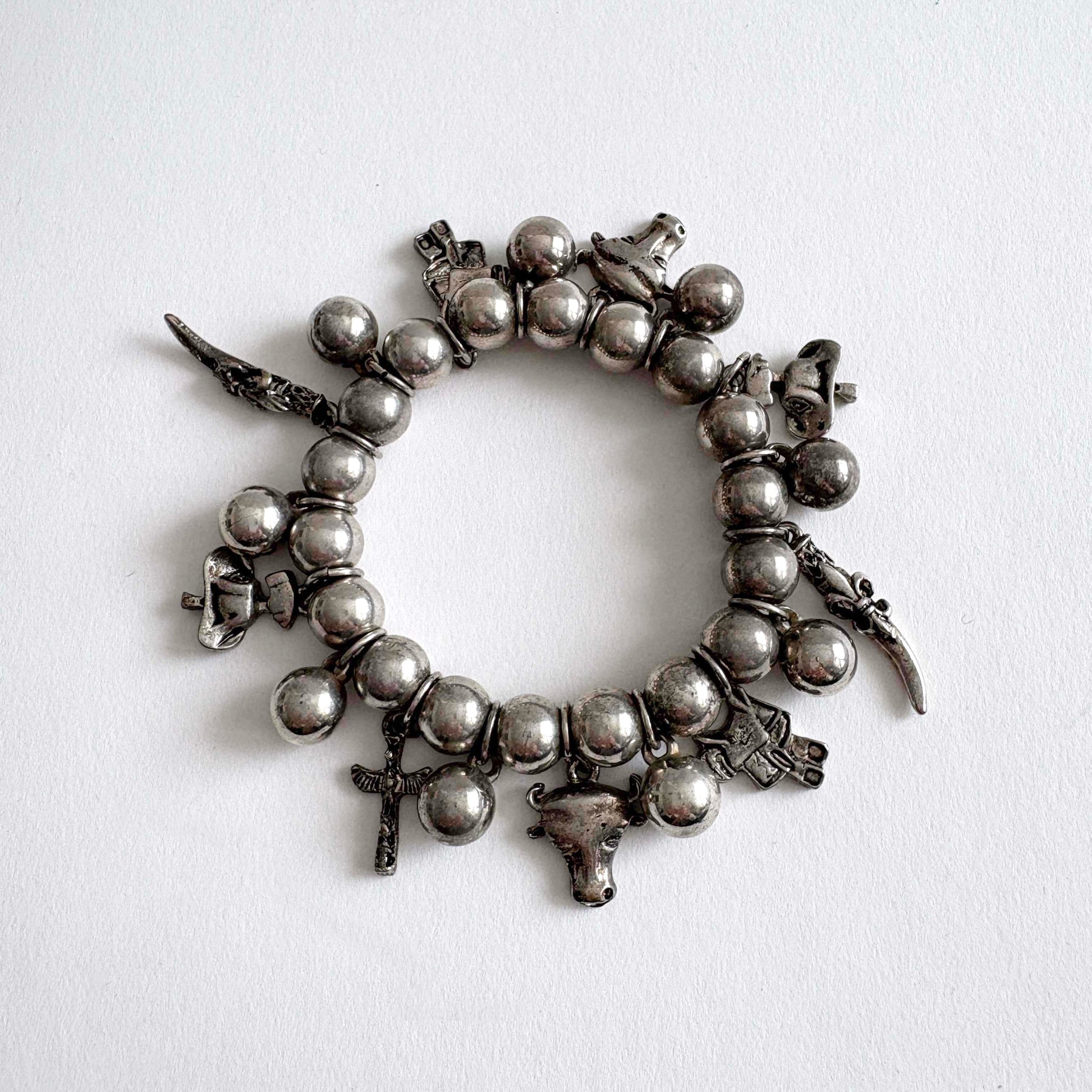Vintage silver-tone Southwestern charm stretch bracelet with beaded design and dangling Western-inspired charms on white background