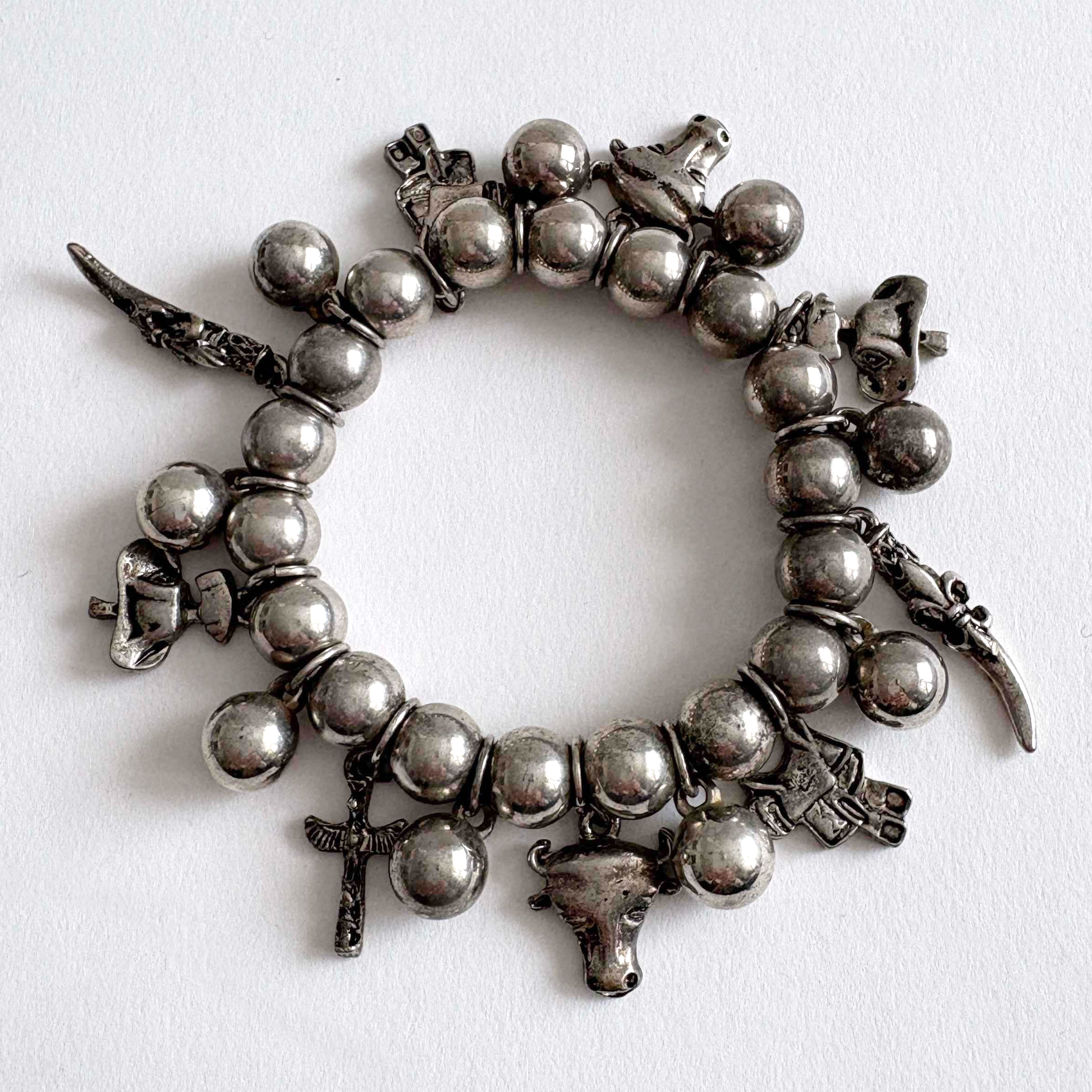 Vintage silver-tone Southwestern charm stretch bracelet with beaded design and dangling Western-inspired charms on white background