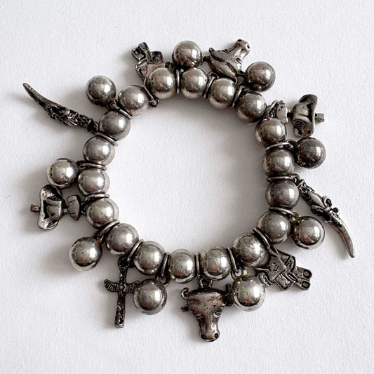 Vintage silver-tone Southwestern charm stretch bracelet with beaded design and dangling Western-inspired charms on white background