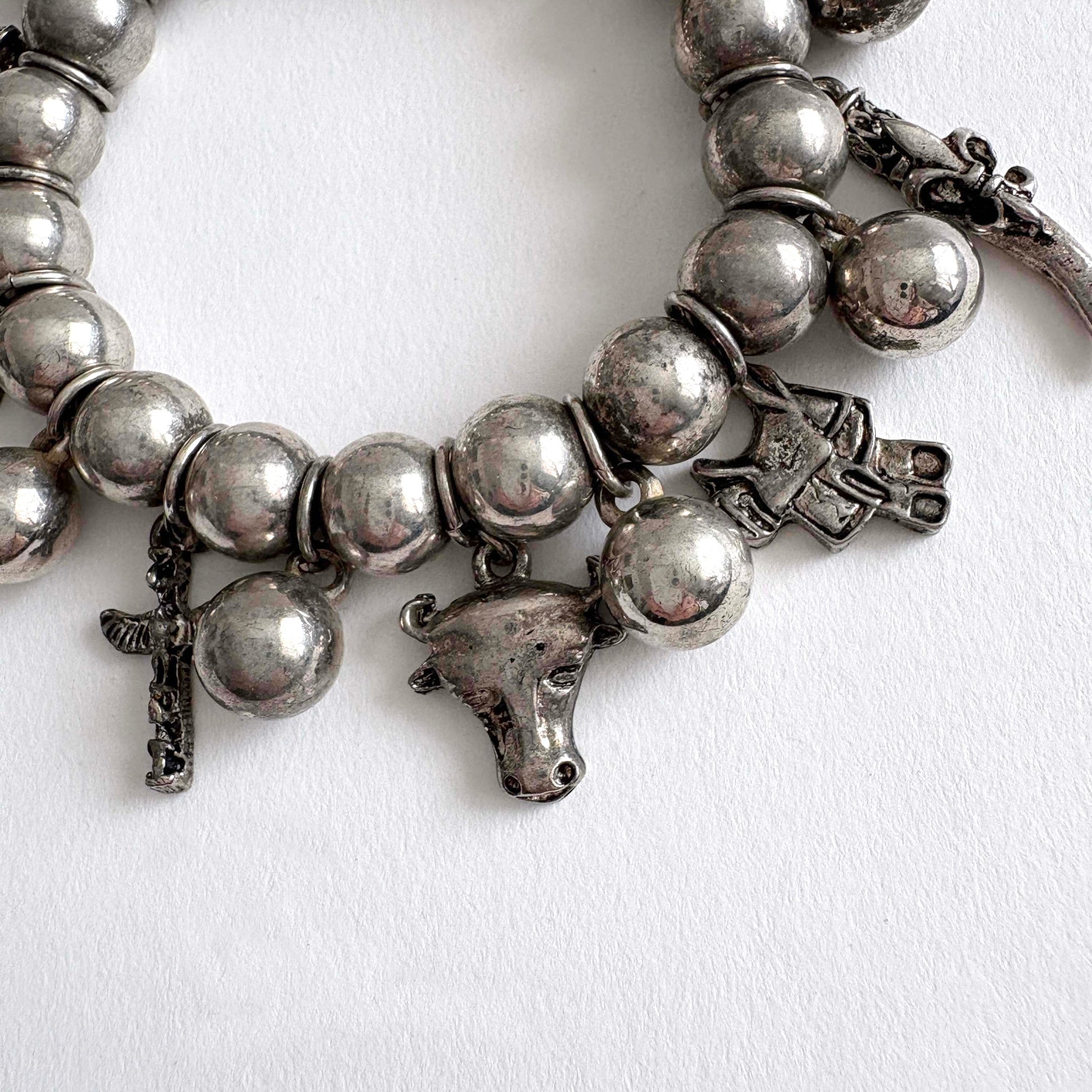 Silver tone beaded bracelet with southwestern charms and beads on a white background