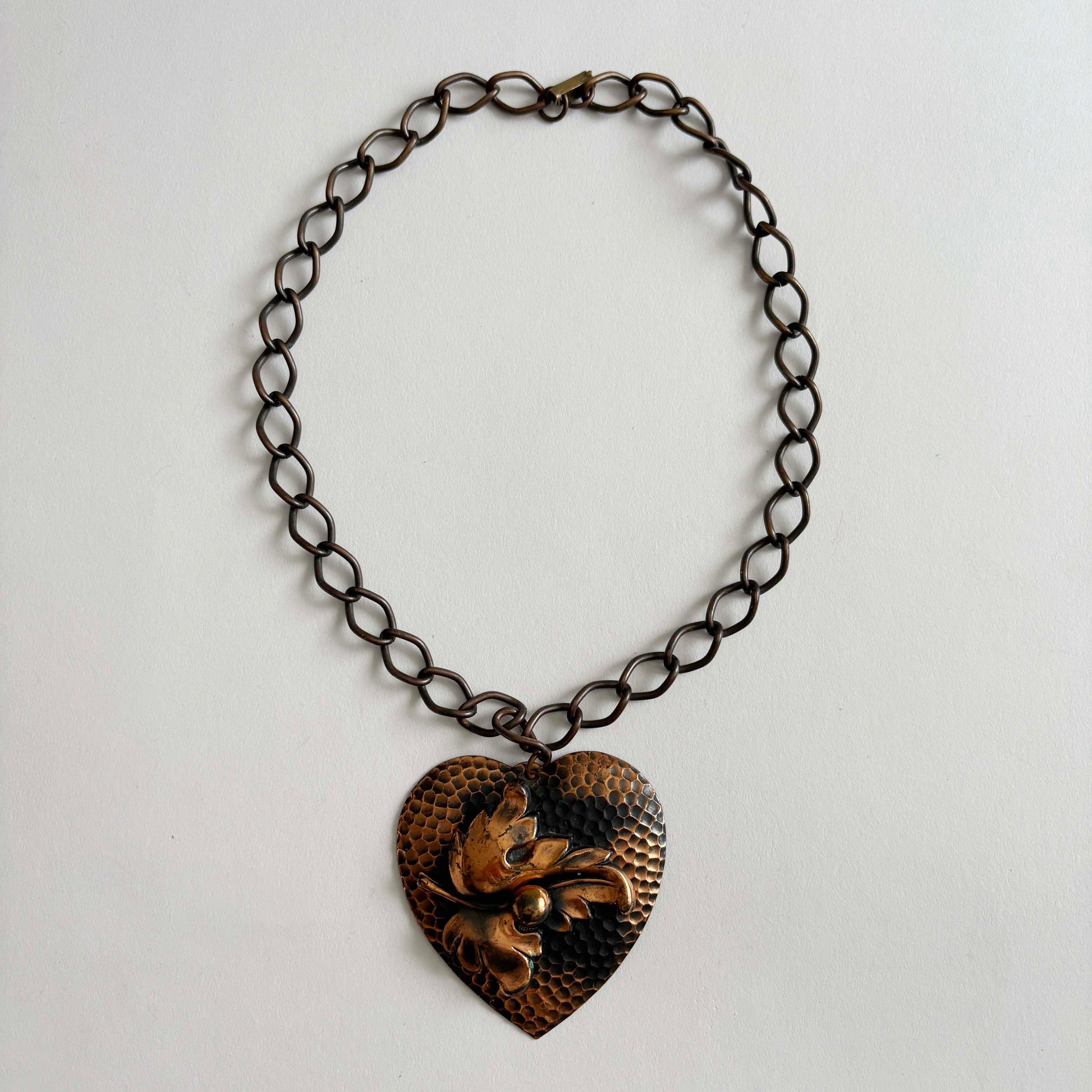 Vintage 1950s hammered copper heart pendant necklace with sculptural leaf motif on chunky copper chain, mid-century modern artisan jewelry.